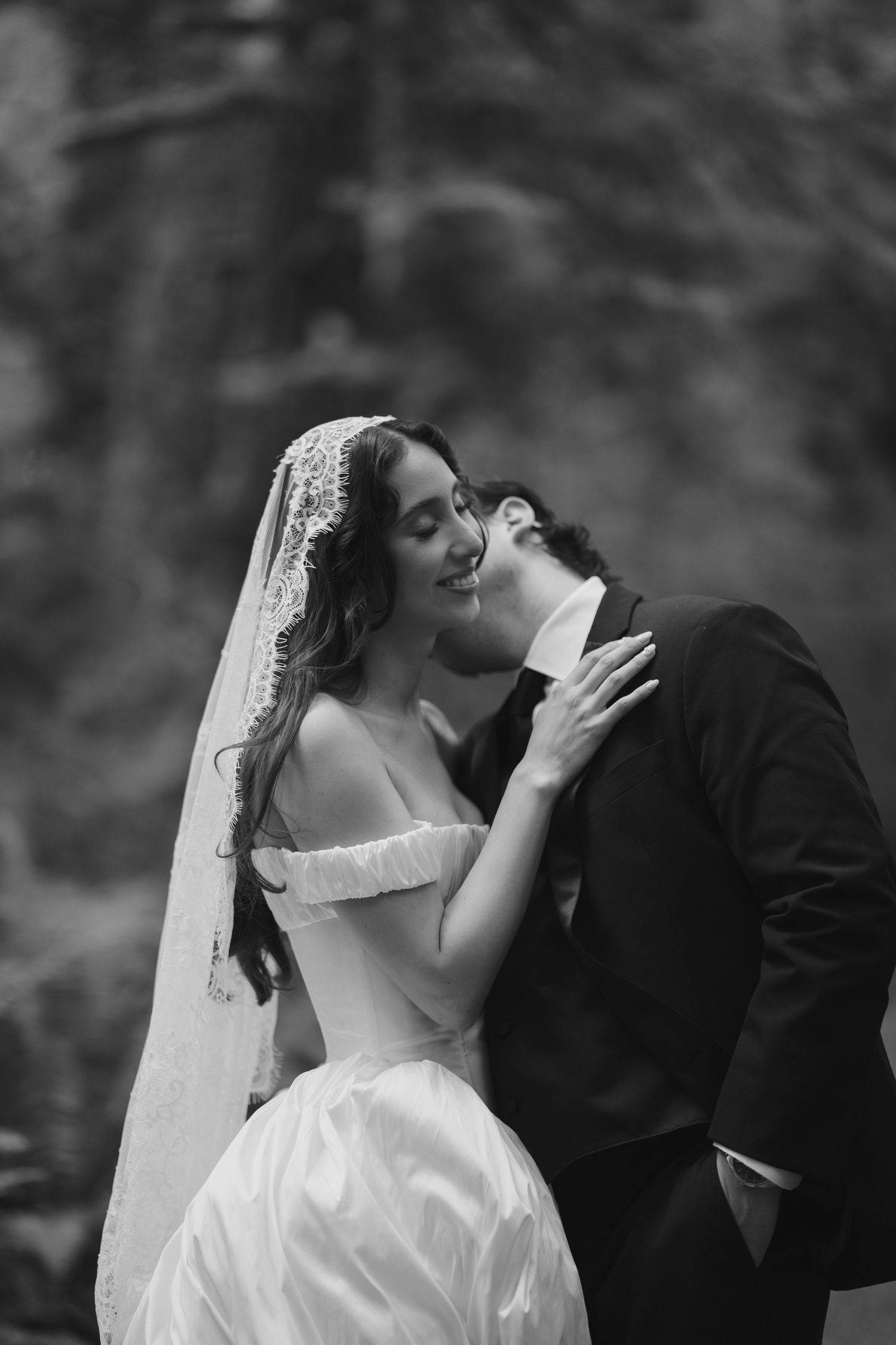 A romantic black and white wedding photo sequence showing a couple sharing a passionate kiss outdoors.