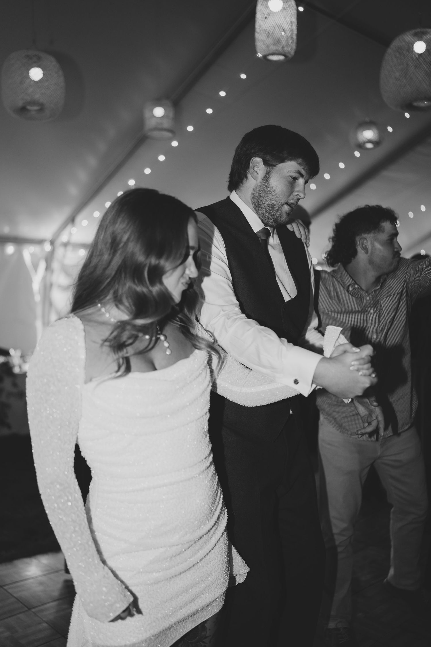 Black and white sequence of couples dancing together at a wedding reception under string lights.