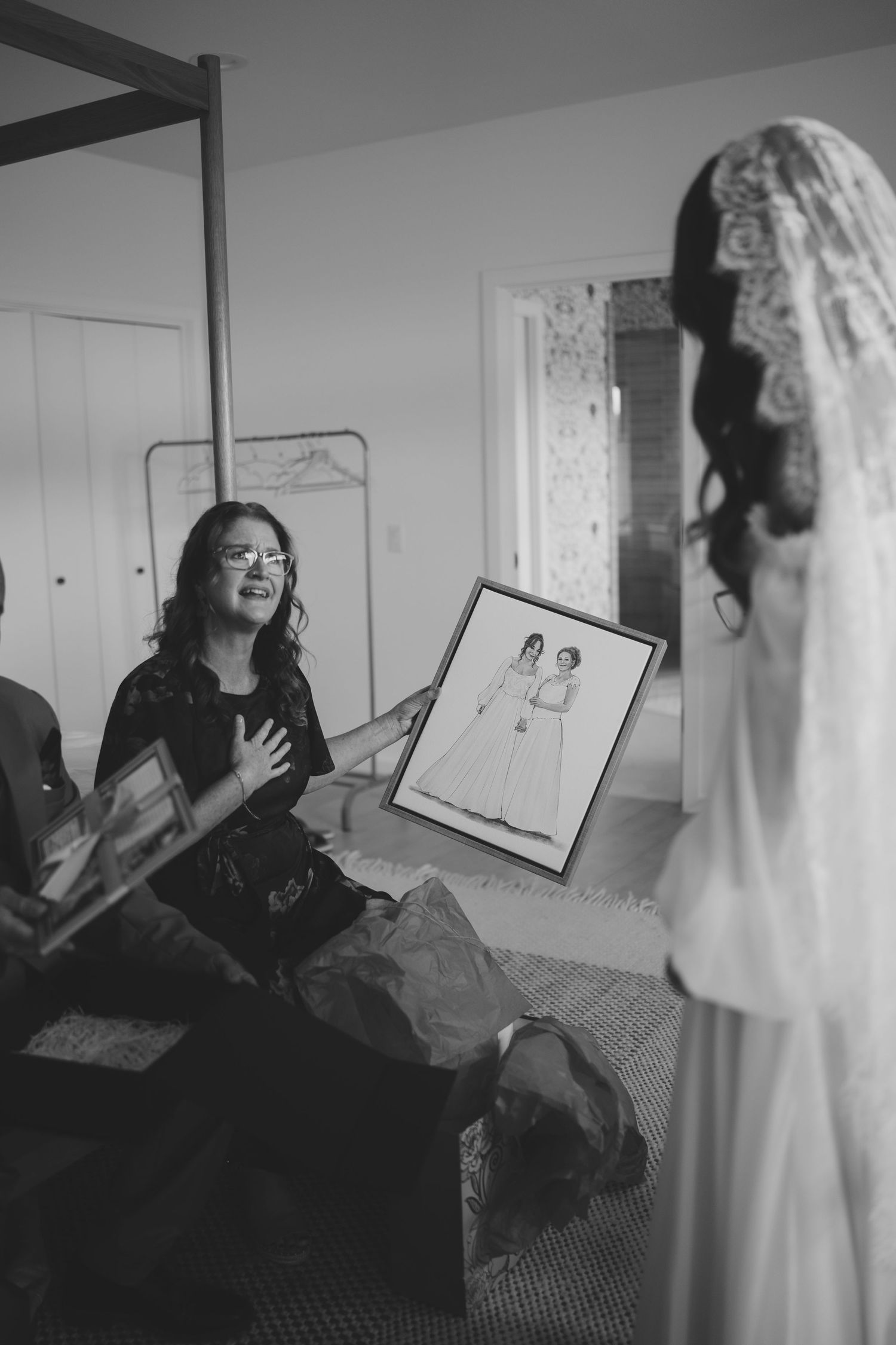 Black and white photo showing people looking at sketches and artwork during wedding preparations.