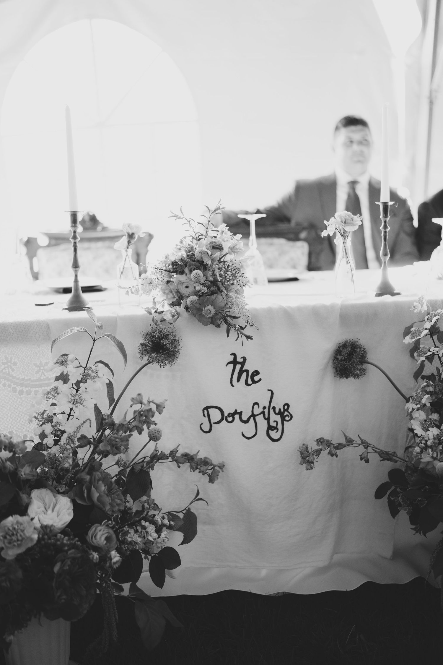 Elegant floral arrangements and decor line a white tablecloth at an upscale event setting.