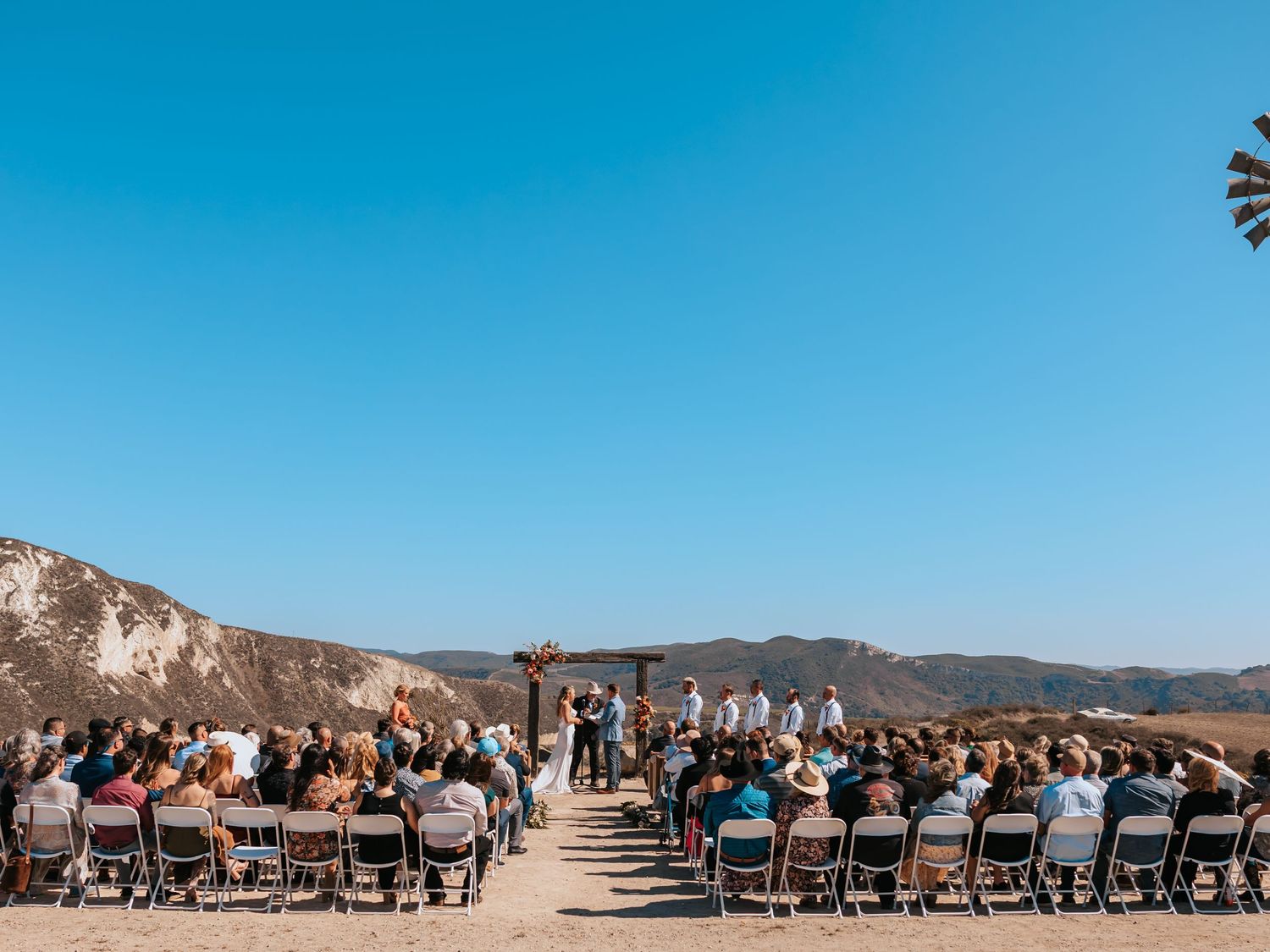 Rows of wooden chairs set up for an outdoor wedding ceremony with mountain range views in the background.