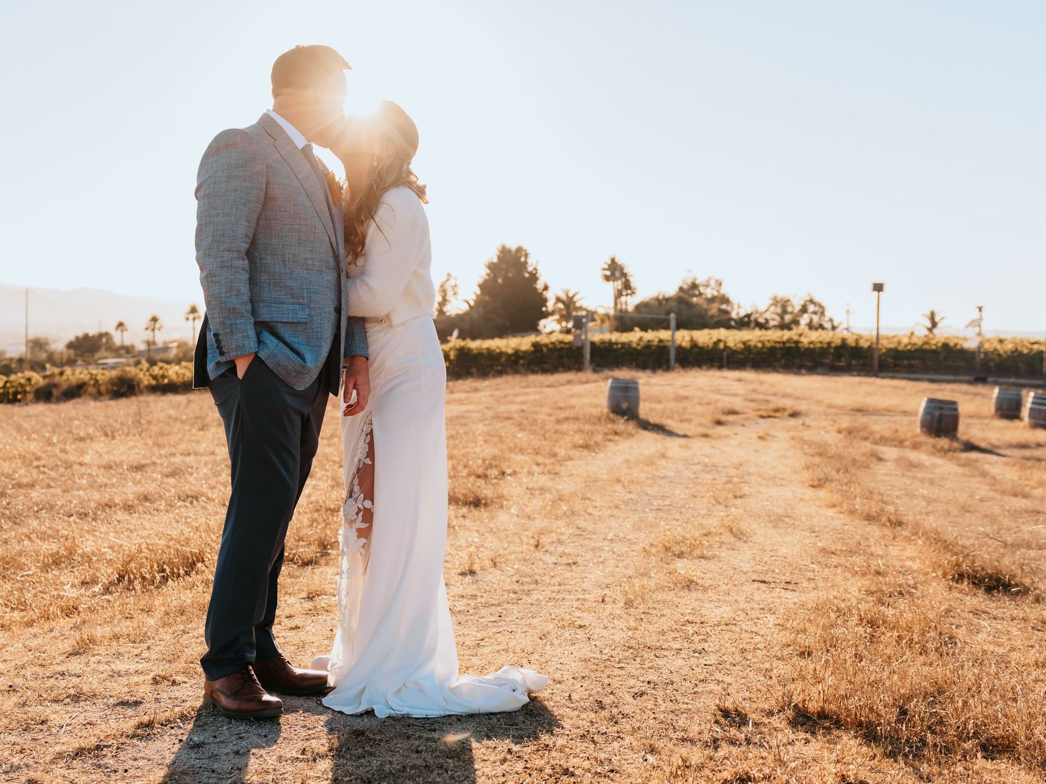 A couple embraces in a sun-drenched outdoor setting at sunset, creating a romantic silhouette against the warm sky.