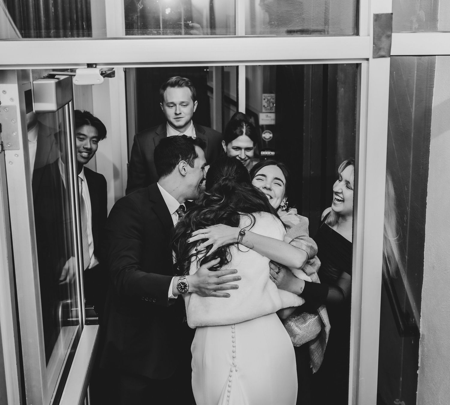 Bride hugging wedding guests in joyful black and white reception photo.