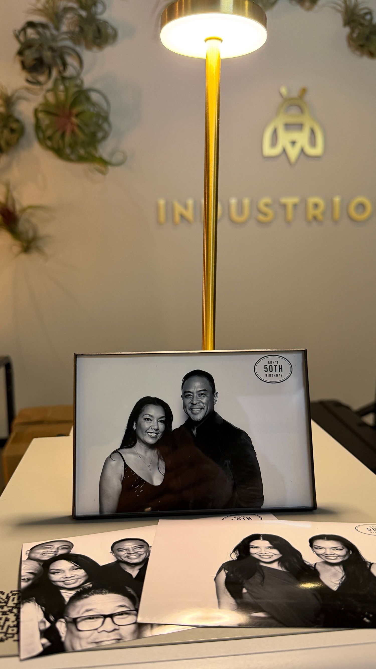 Black and white photo booth prints displayed at an Industrious event, featuring couples posing for a 50th birthday celebration. Walnut Creek