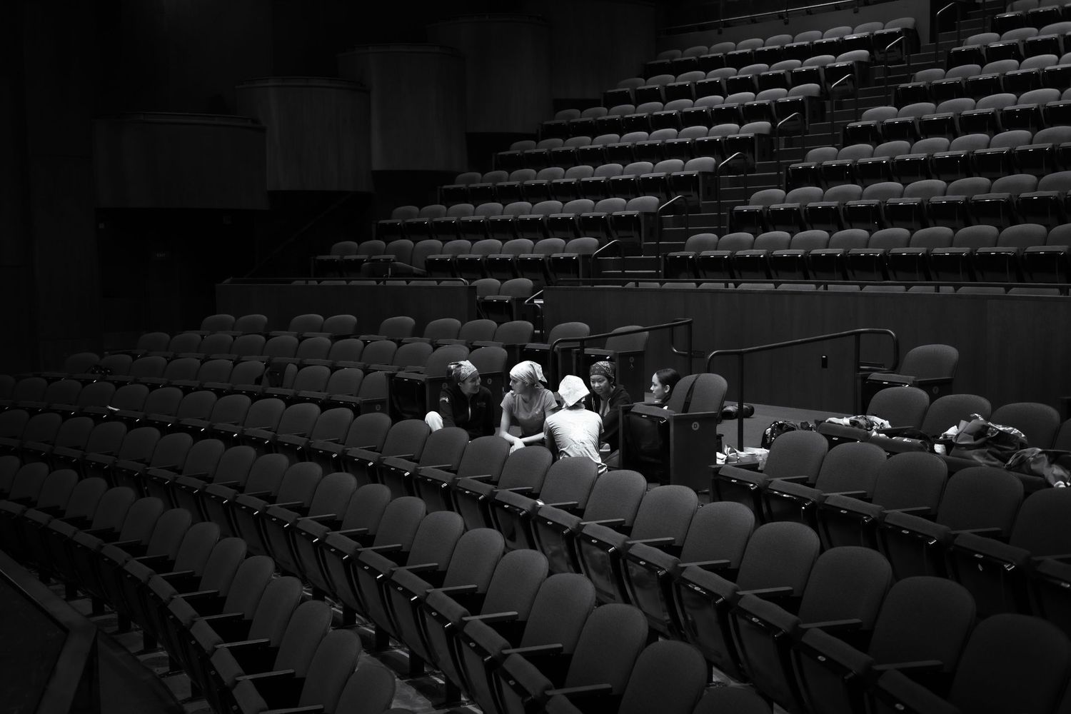 Black and white photo of a small group seated in an otherwise empty theater auditorium with rows of vacant chairs. Las Positas College