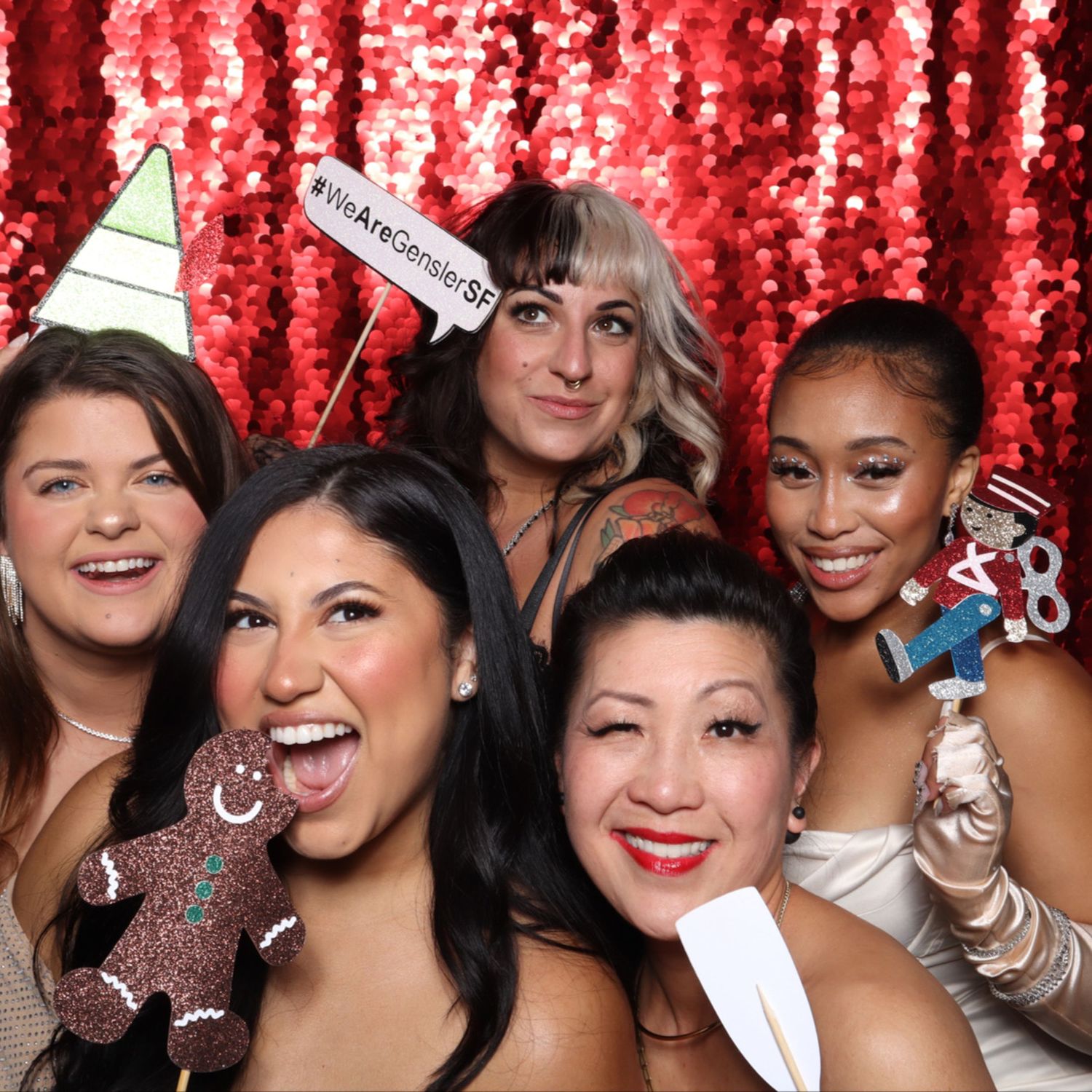 Five women pose cheerfully at a festive photo booth with red sequin backdrop at the Gensler San Francisco party.