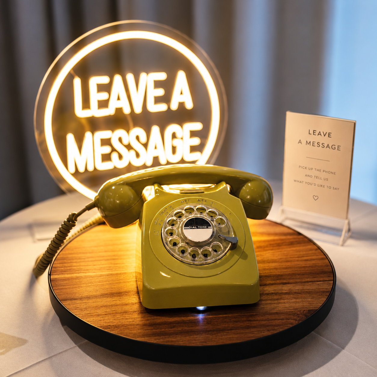 Vintage green rotary phone on wooden stand with glowing neon 'Leave A Message' sign, perfect for wedding or event decor.