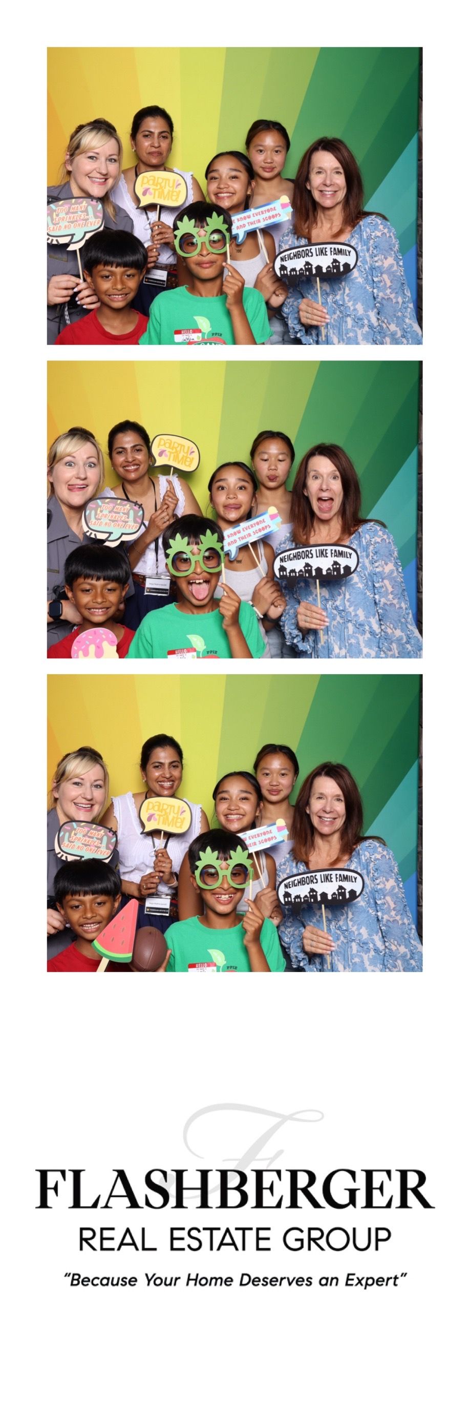 Group photo booth strip at Flashberger Real Estate Group event with adults and children holding fun props and signs.
