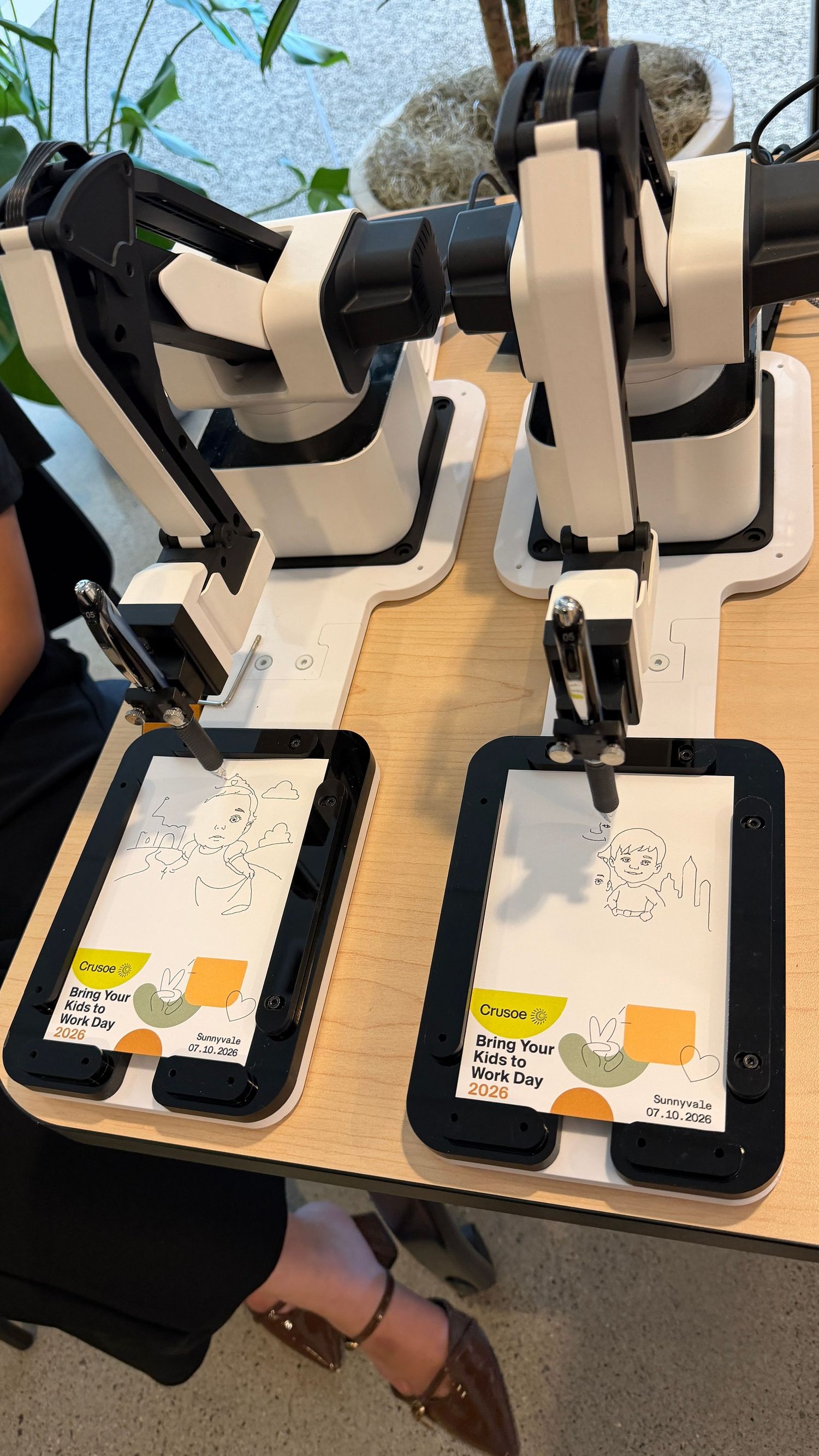 Crusoe Bring Your Kids to Work Day drawing robots with tablets displaying cartoon sketches. Our AI Sketchbot hard at work.