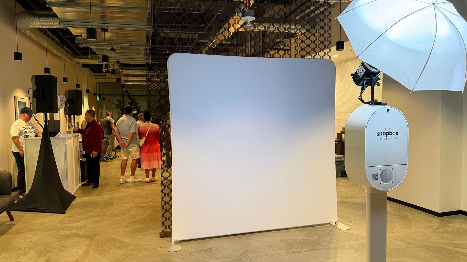 Professional photo booth setup with white backdrop, umbrella light, and camera on stand in modern event space. Industrious, Walnut Creek.