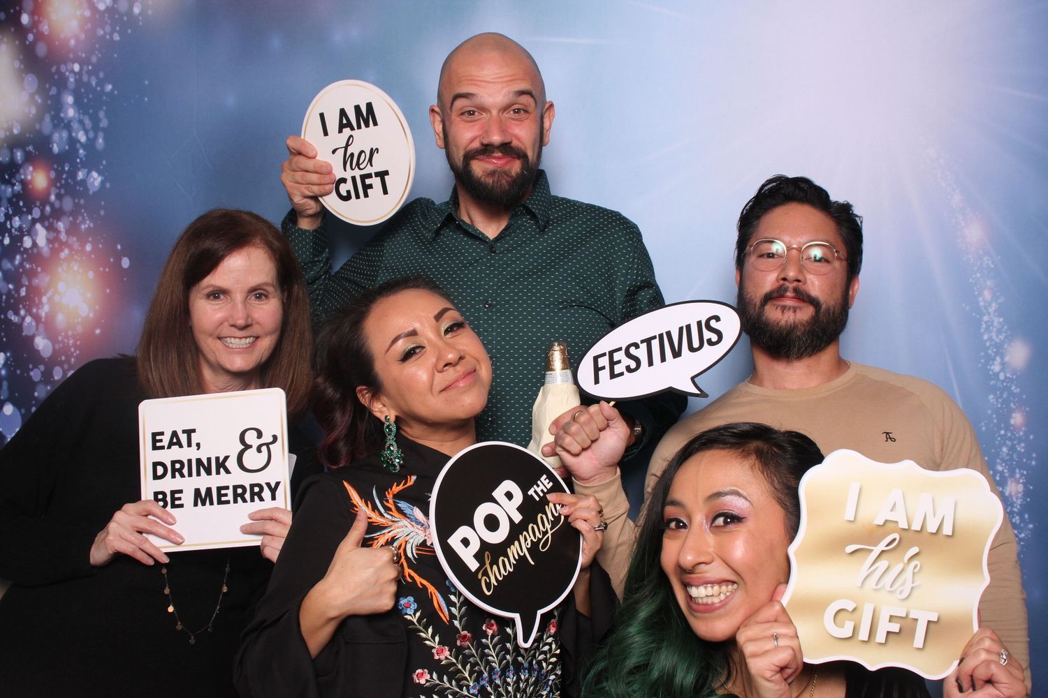 Group of five friends posing at a festive photo booth at Festivus at KBM Hogue's office in San Jose