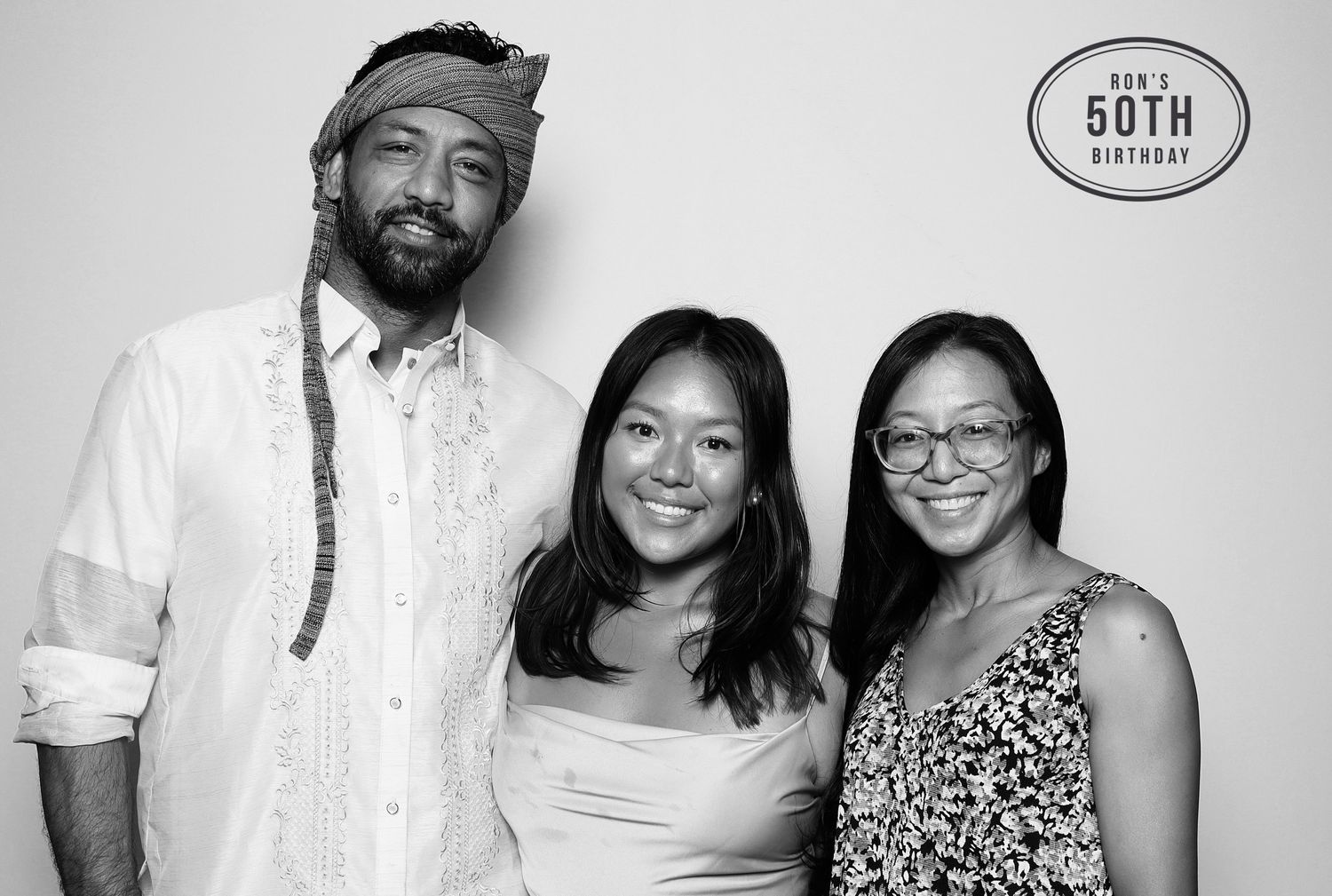 Black and white photo booth picture of three smiling friends at a 50th birthday celebration party. Industrious, Walnut Creek.