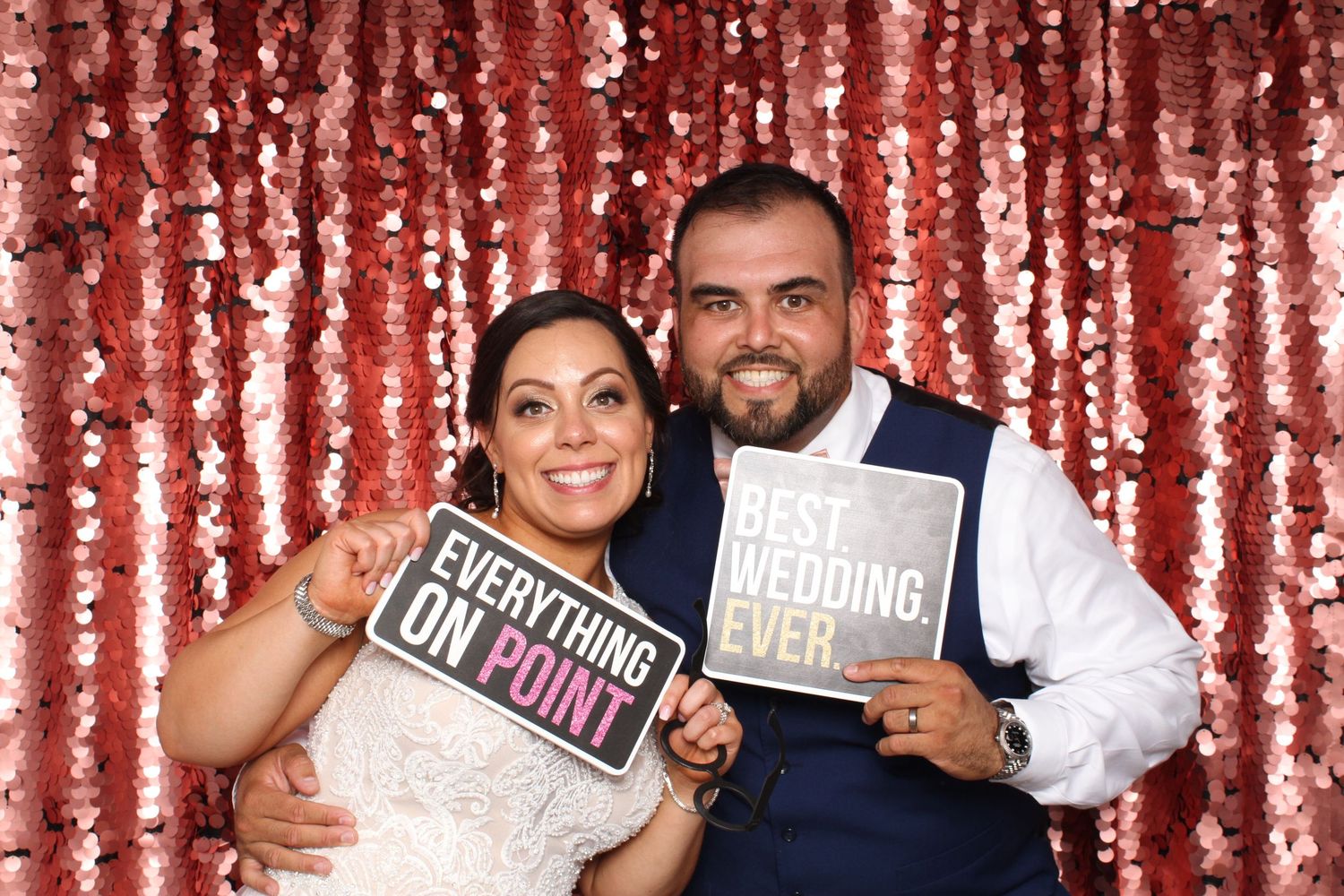 Couple smiling at wedding at Callippe Golf Club in Pleasanton with sequin backdrop holding fun signs.