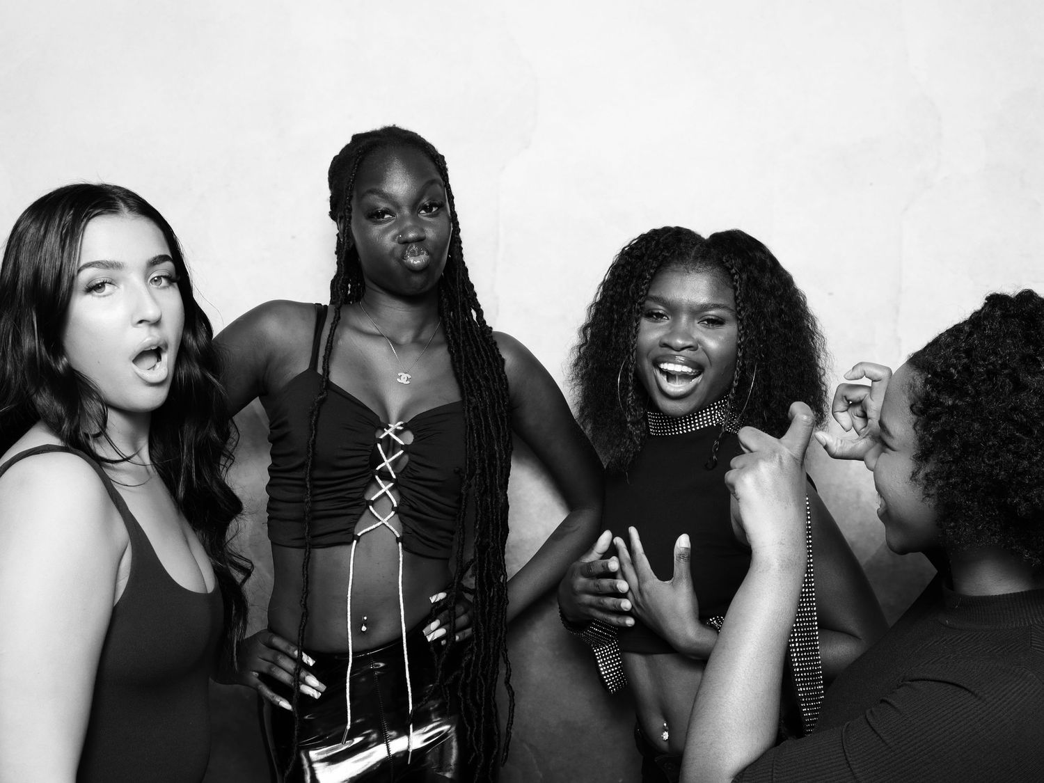 Four women posing together in a black and white photo booth shot, laughing and having fun.