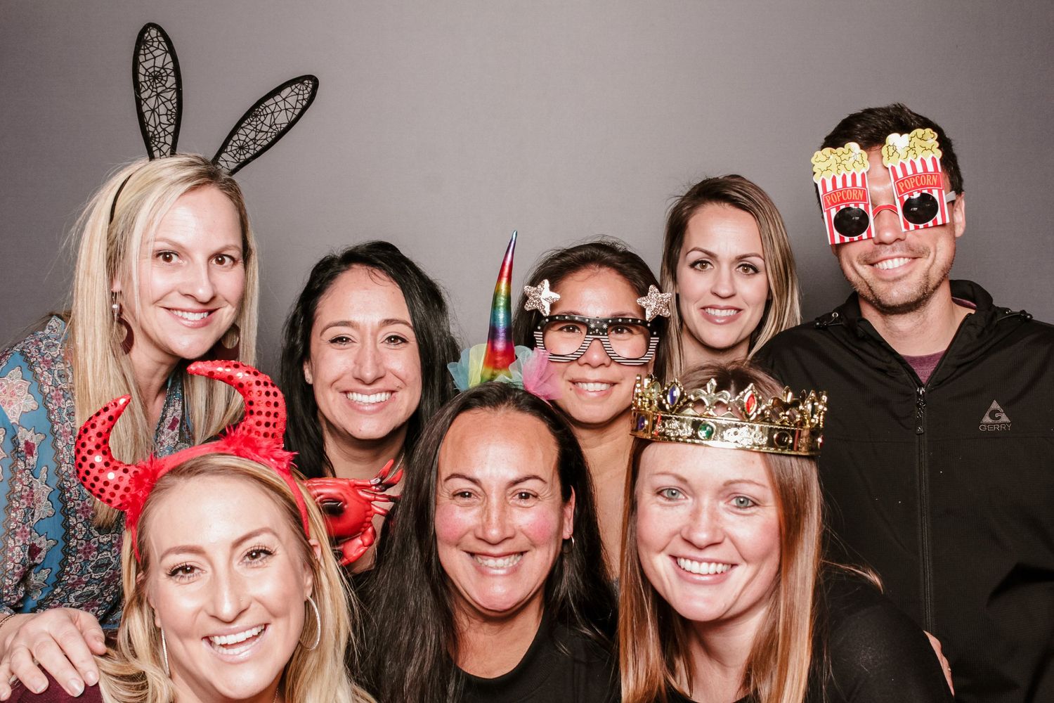 Group of friends posing in a photo booth wearing fun props at a wedding at the Claremont Hotel.