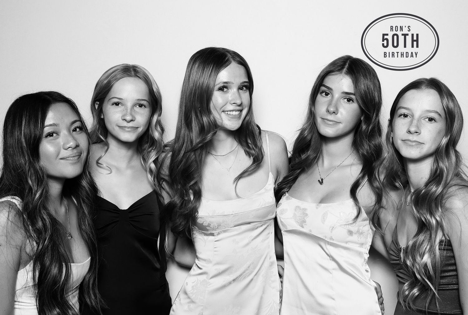 Five young women pose together smiling at a 50th birthday party photo booth in a black and white photo. Industrious, Walnut Creek.
