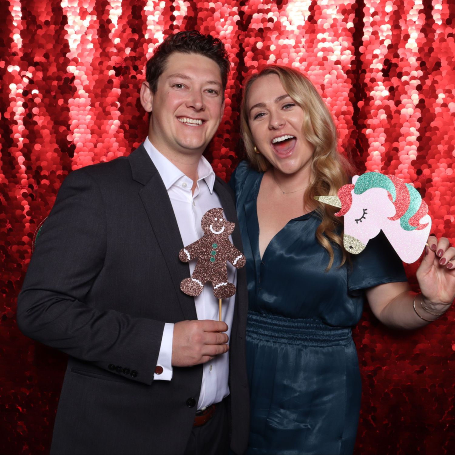 Gensler Holiday Party Couple posing with holiday props in front of red sequin backdrop at festive party photo booth.