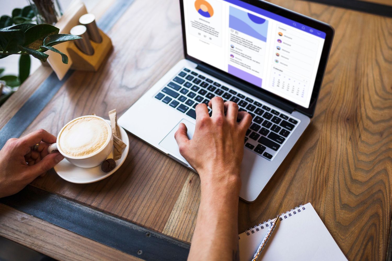Person working on laptop with analytics dashboard, coffee cup nearby on wooden desk in cafe setting.