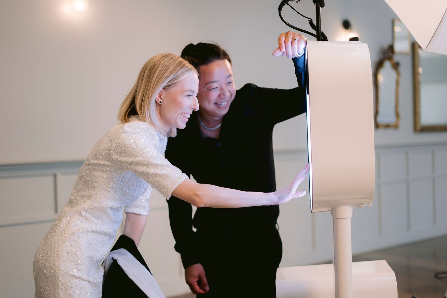 Two guests laugh as they review their photos on the Lune LED photo booth touchscreen.