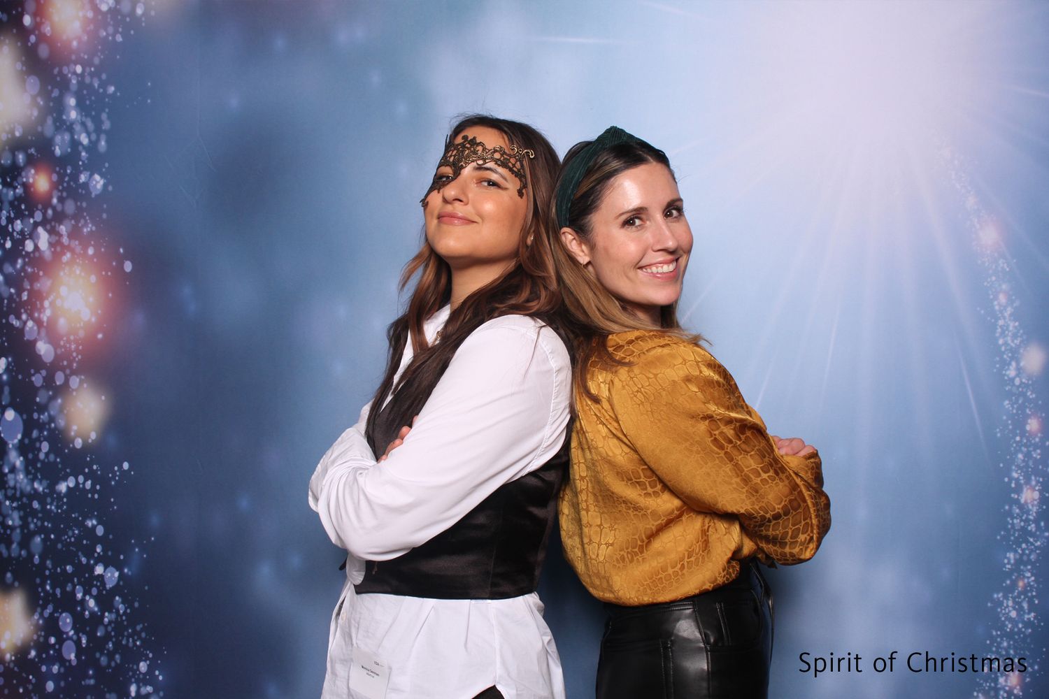Two women in pirate costumes posing back-to-back in festive Christmas-themed photo booth.