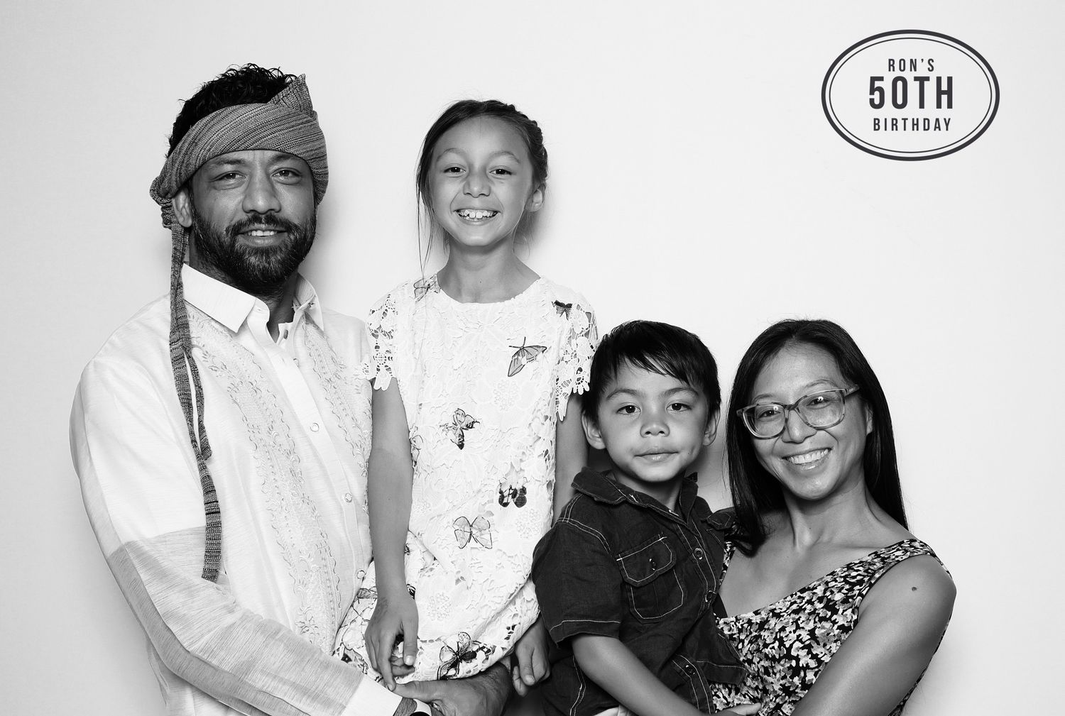 Family of four posing together at a 50th birthday at industrious in Walnut Creek. The man is wearing barong Tagalog, Filipino inspired shirt