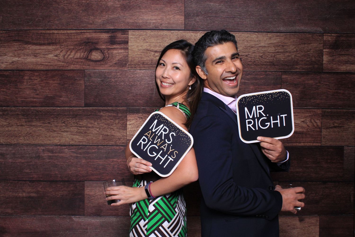 Couple posing back-to-back at wedding photo booth holding Mr. Right and Mrs. Always Right signs, smiling joyfully.