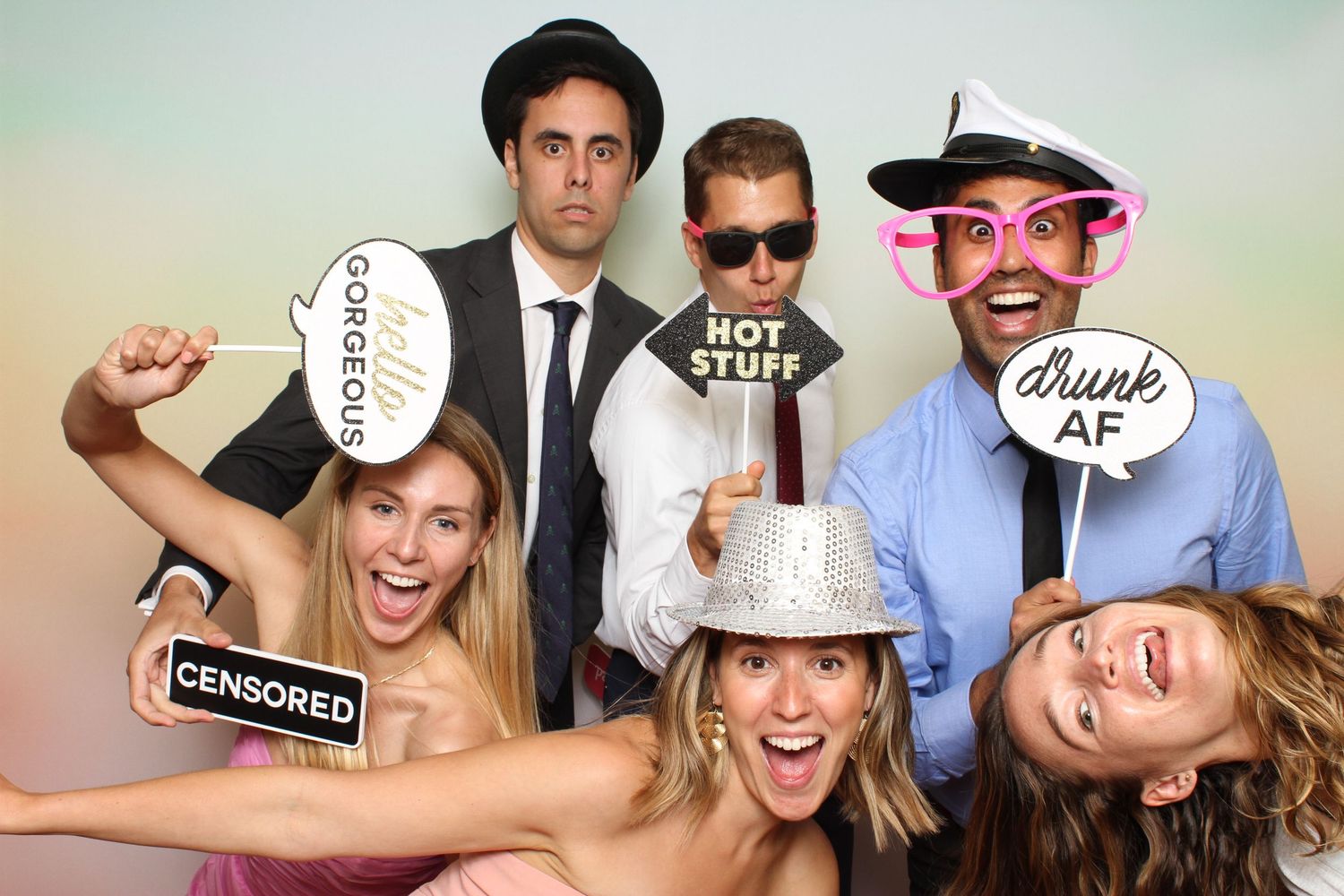 Group of friends posing in a photo booth with fun props including censored, hot stuff, and drunk AF signs. Peacock Gap Golf Club