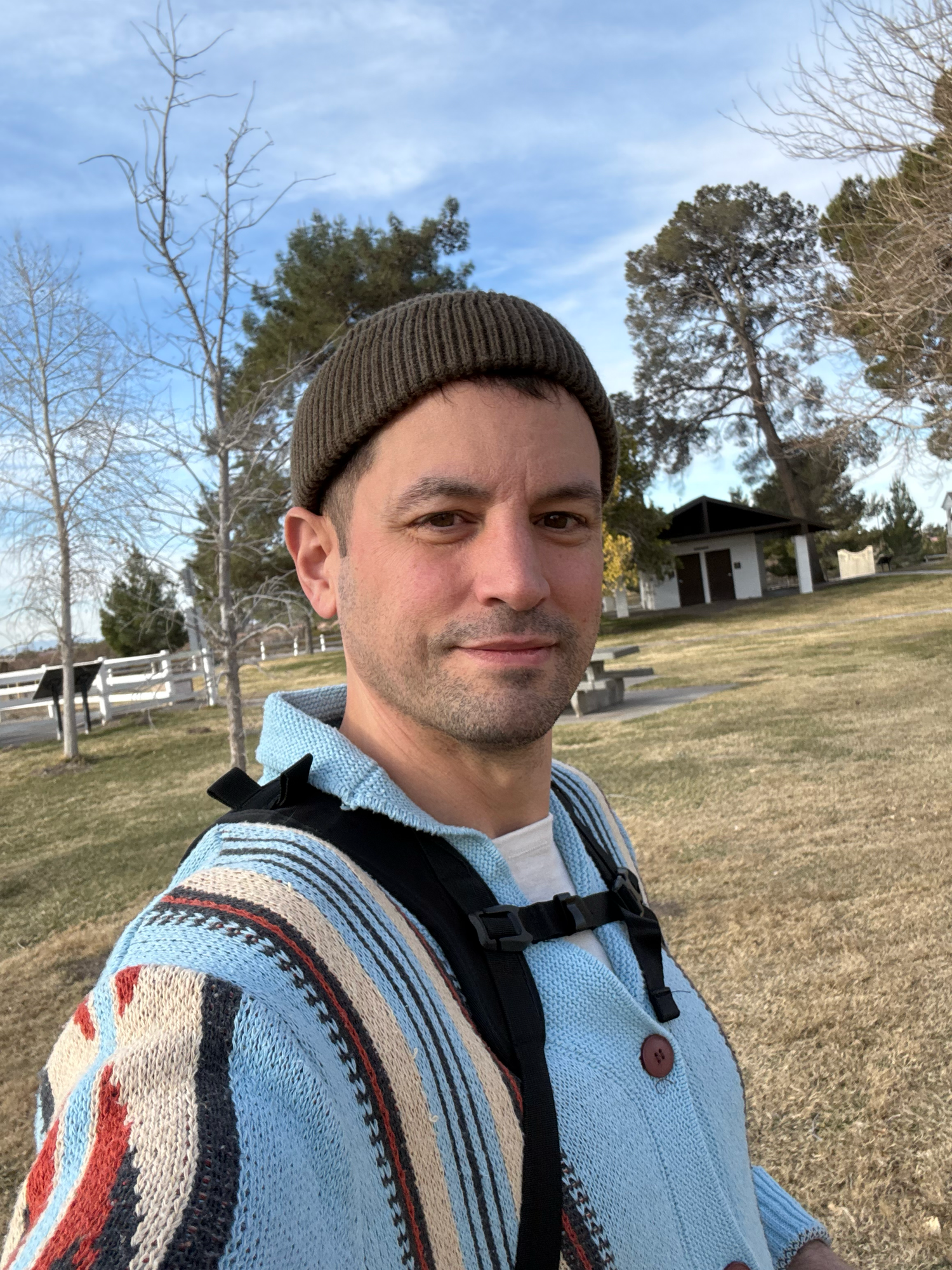 Nick Streeter wearing brown beanie and patterned sweater takes outdoor selfie at a park in winter.