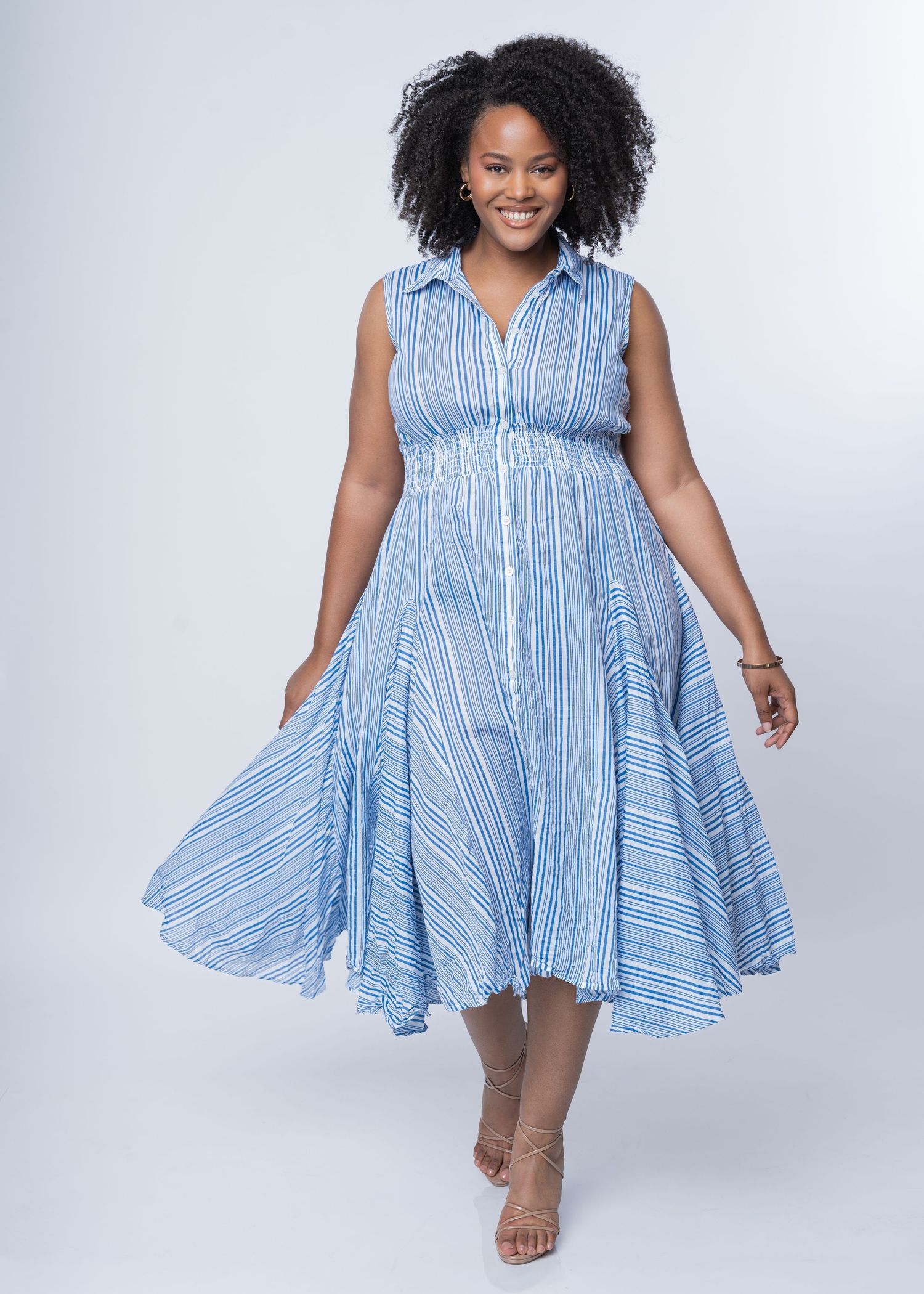 Woman wearing a blue and white striped sleeveless midi dress with collar and flared skirt, paired with nude heels.