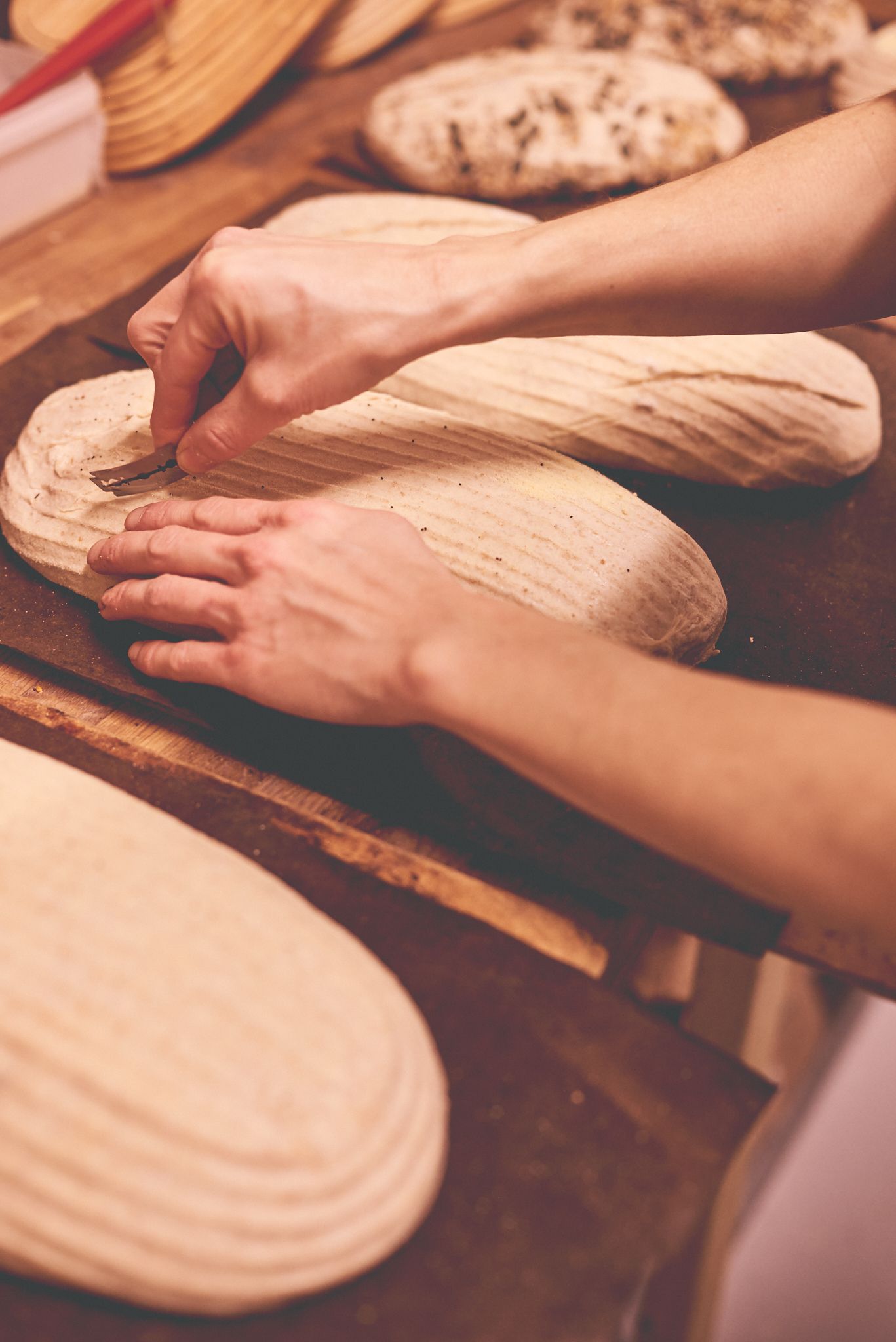 Hands scoring sourdough during a natural brand photoshoot for a Suffolk bakery