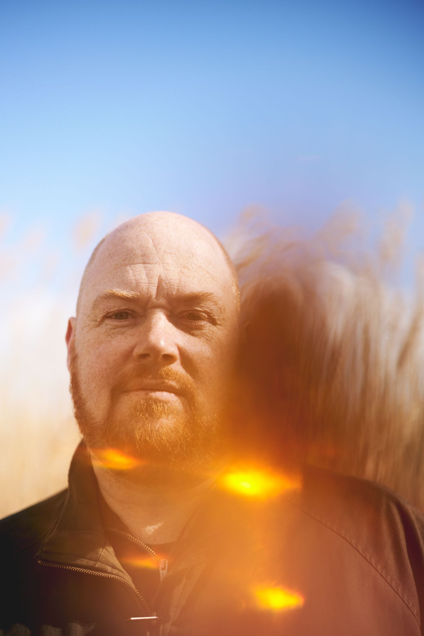 Composer standing against blue sky at Snape, Suffolk during a natural portrait session