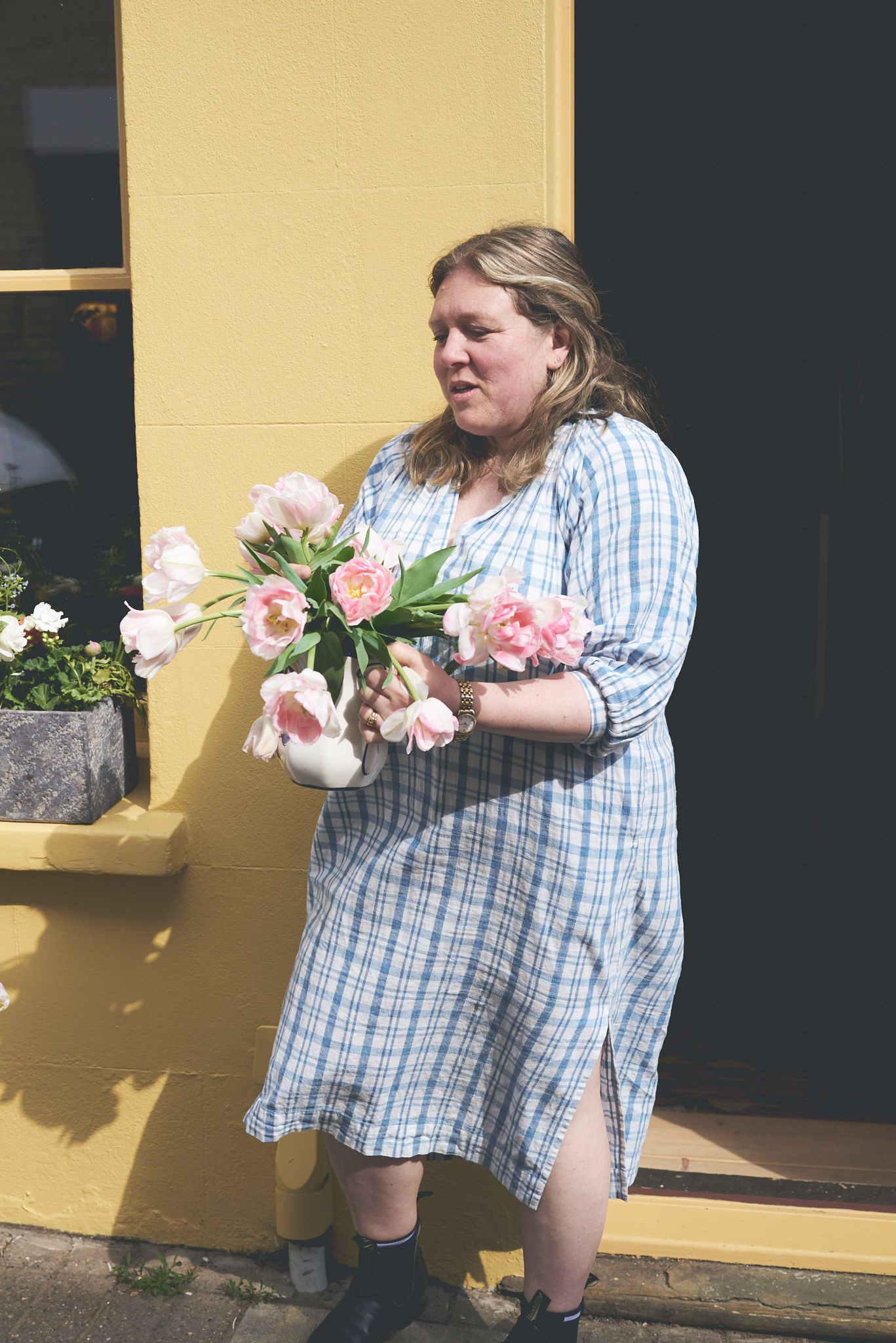 woman holding flowers against yellow wall woodbridge during a brand photoshoot