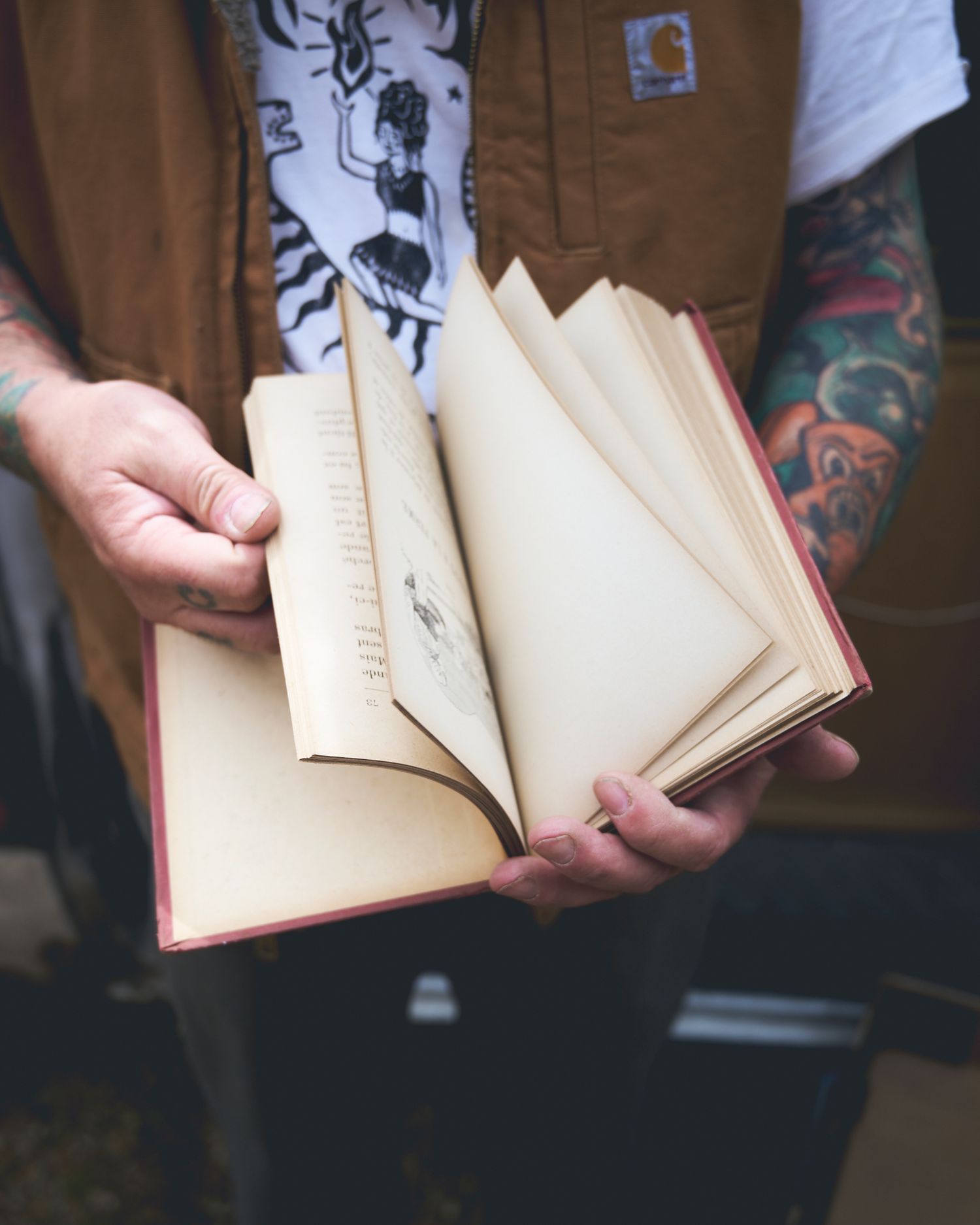 Close-up of man with tattoed arms flicking through a book during a small business photoshoot near Woodbridge