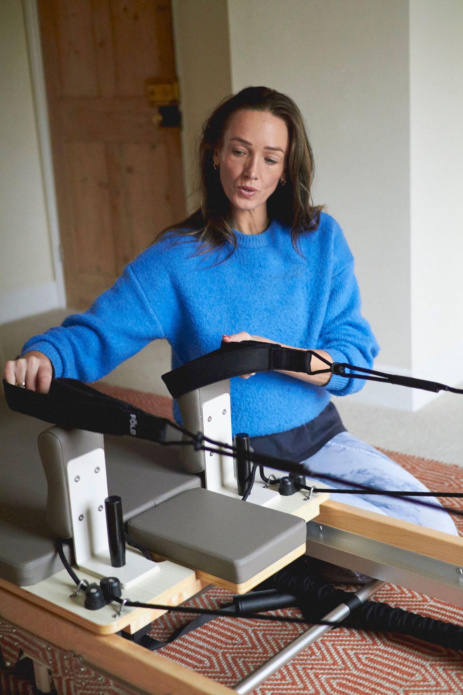 Bodykynd Pilates instructor sitting next to the reformer at Albany Health in Woodbridge during a brand photoshoot