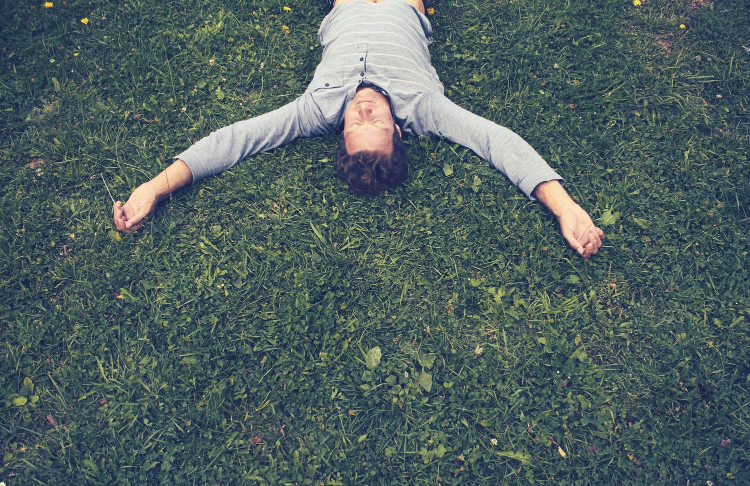 Man lying in grass with eyes closed by Cat Heygate photo