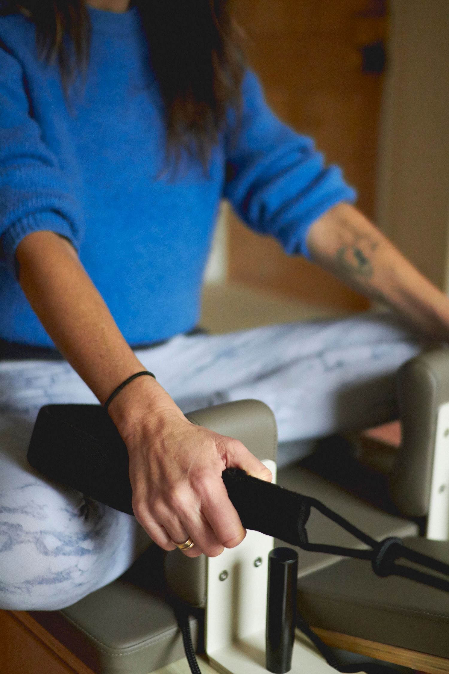 Close‑up of hands holding the reformer Pilates ropes during a brand photoshoot