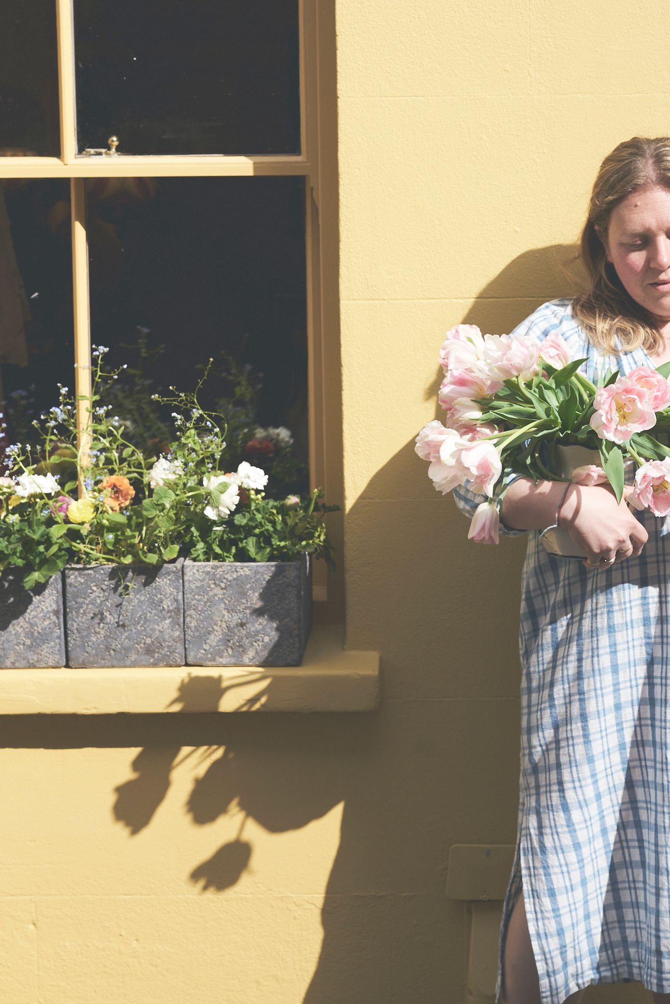 Woman cropped standing against a yellow wall holding flowers for a brand photoshoot Woodbridge
