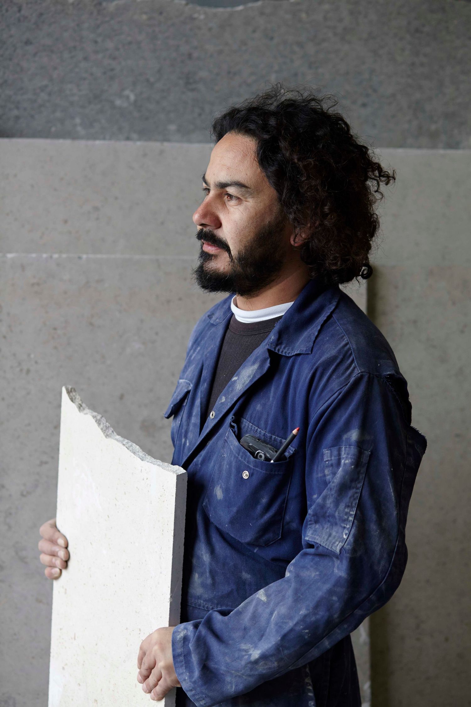 Stonemason holding a piece of marble in his Suffolk workshop during a brand photoshoot