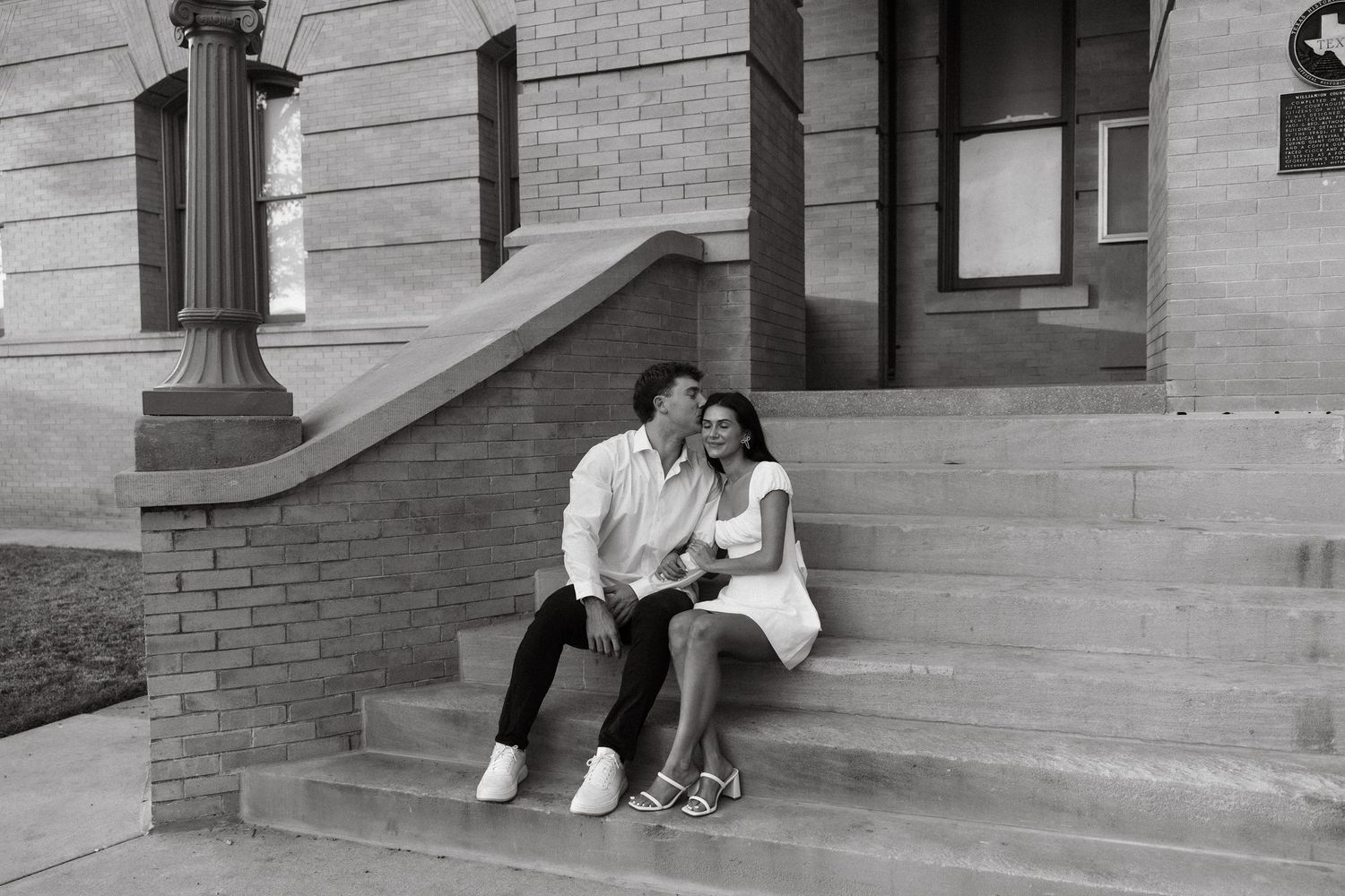 Black and white photo of a couple sitting close together on historic building steps.