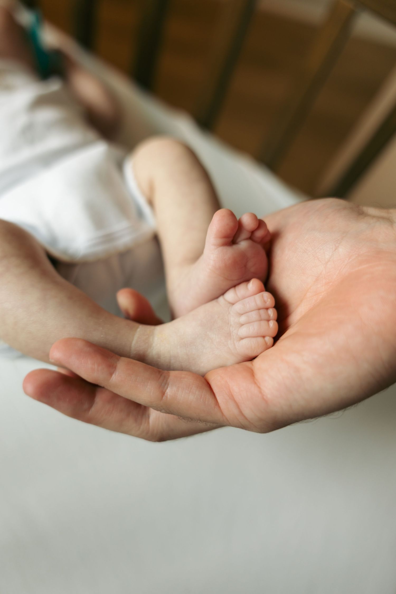 Parent holds tiny newborn baby feet gently in the palm of their hand.