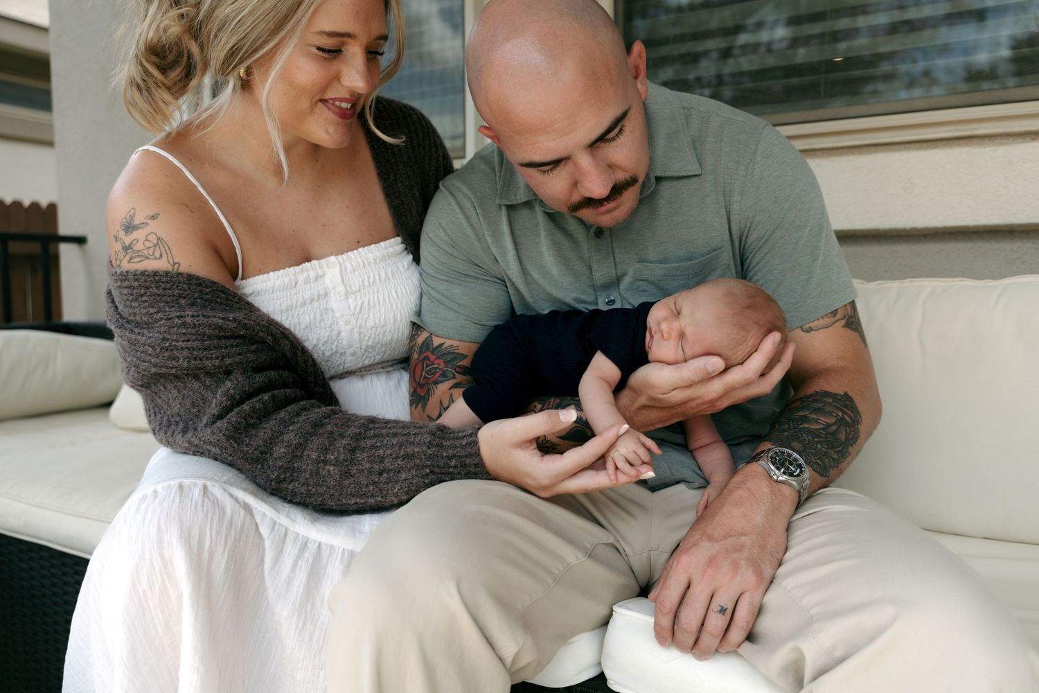 New parents lovingly admire their sleeping newborn baby during an intimate in-home newborn photo session.