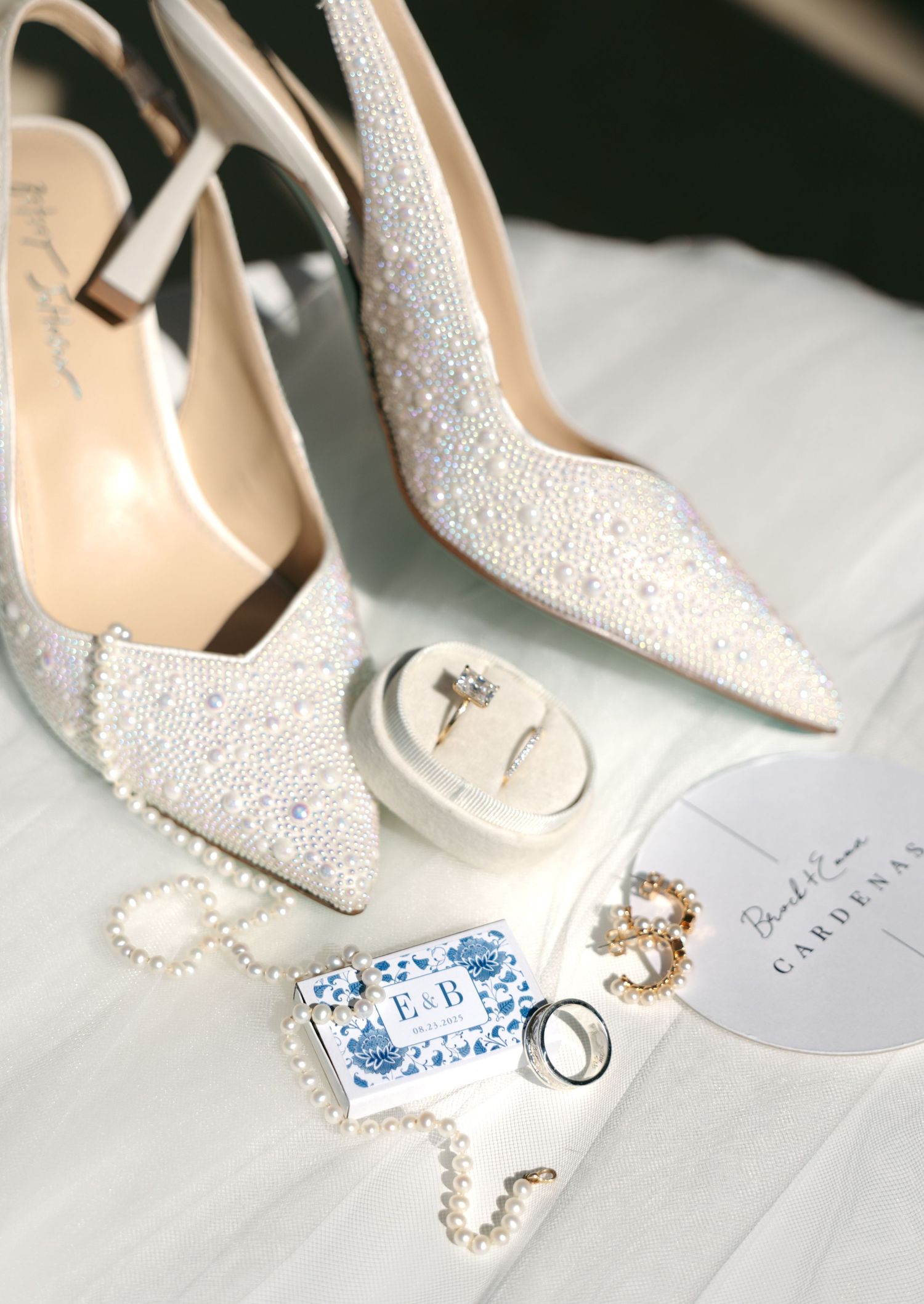 Pearl-encrusted bridal heels styled with diamond ring, pearl necklace, and personalized wedding details.