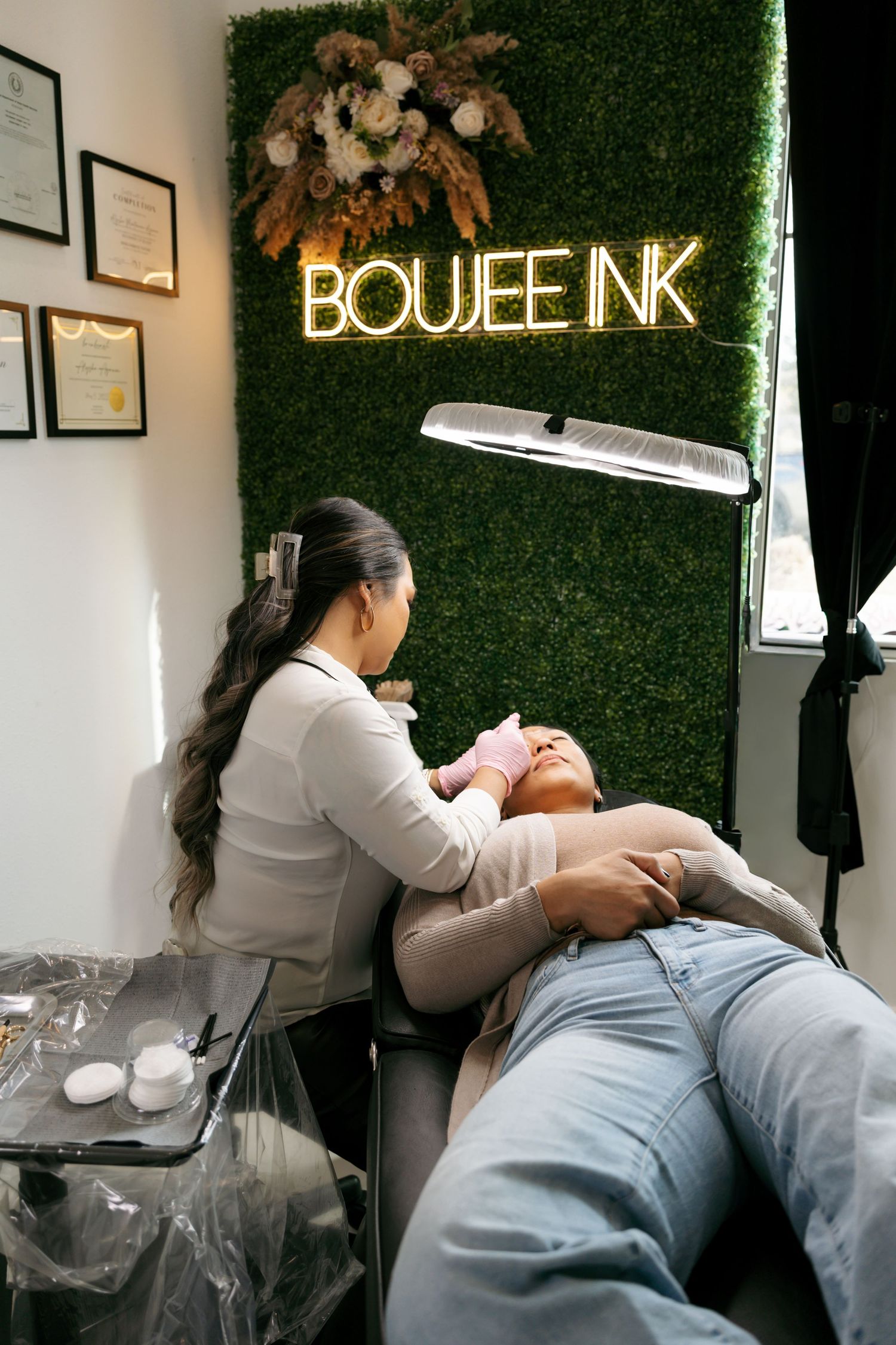 Esthetician performing a facial treatment on a client at Boujee Ink beauty studio.