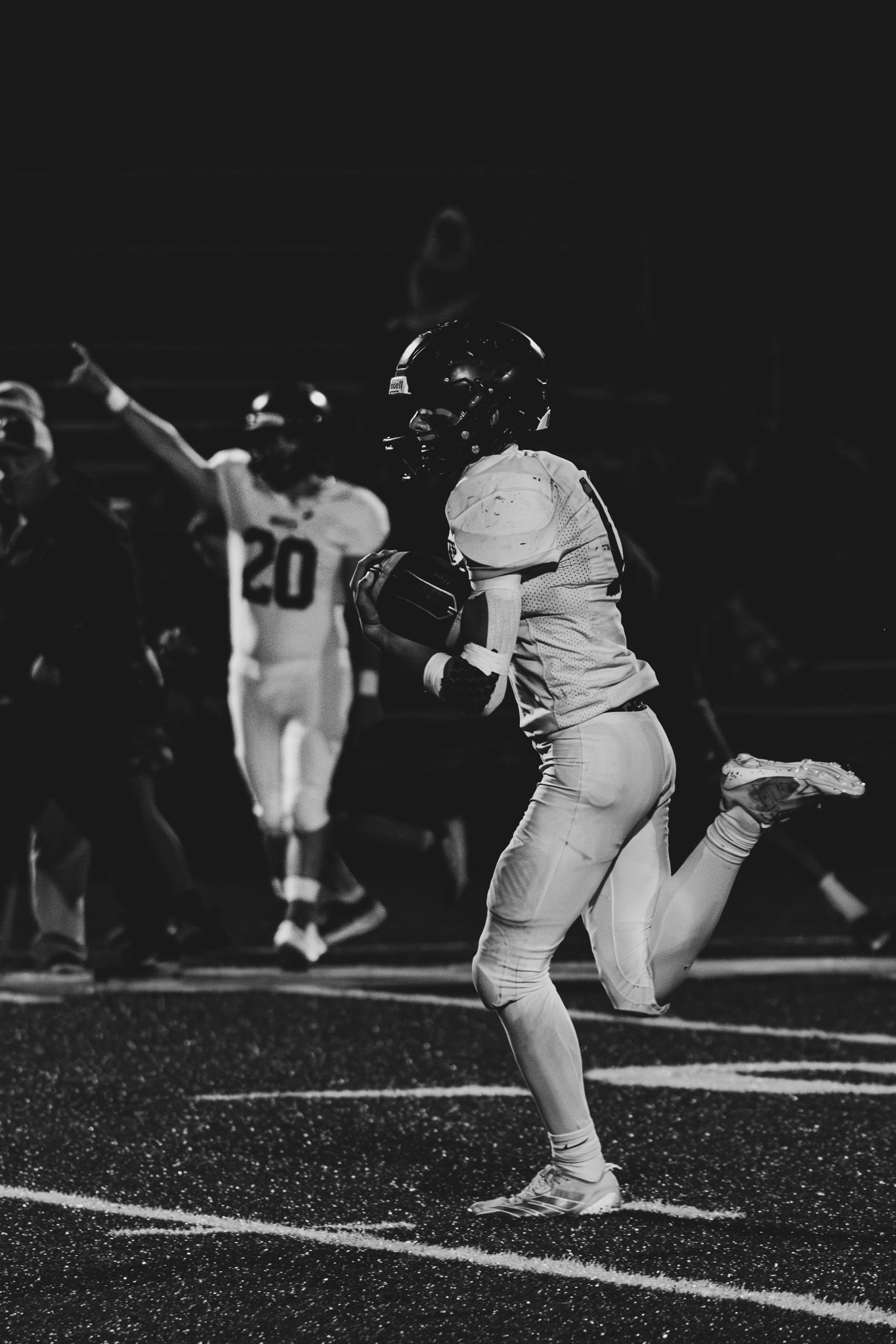 Football player runs into the end zone for a touchdown while a teammate celebrates in black and white photo.