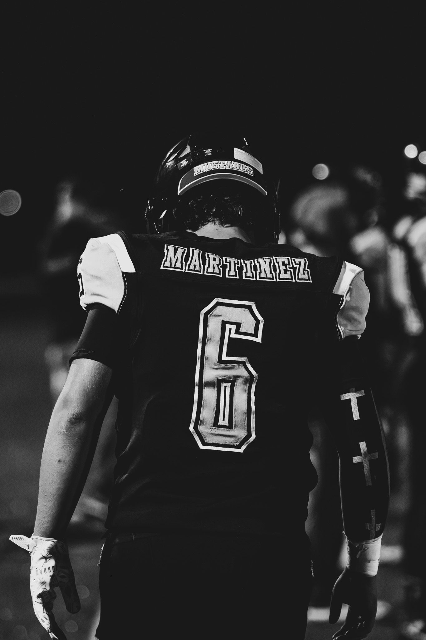 Black and white photo of football player Martinez wearing jersey number 6 standing on field at night.