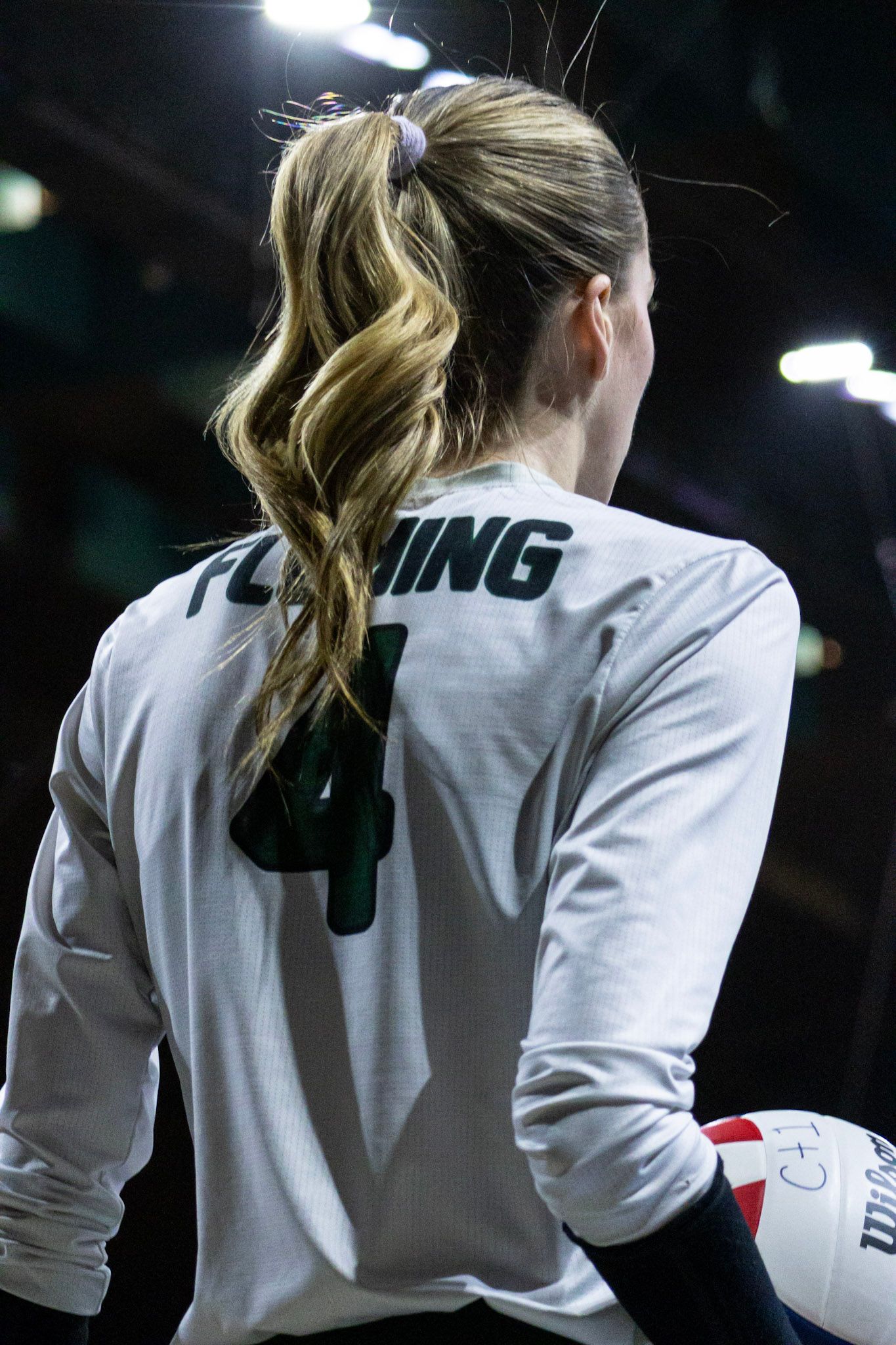 Volleyball player wearing number 4 Fleming jersey holding ball from behind.