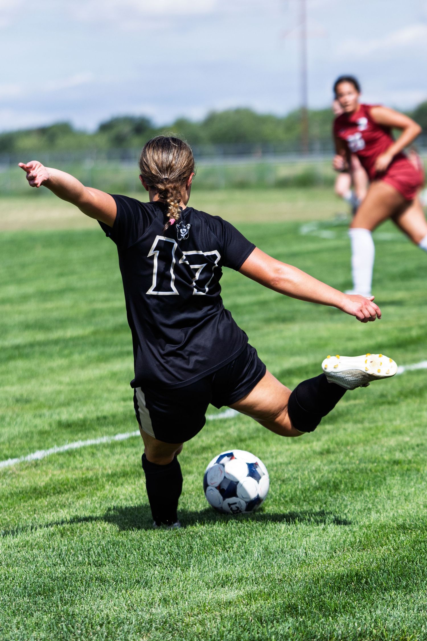 Female soccer player number 17 in black uniform prepares to kick the ball during a match.