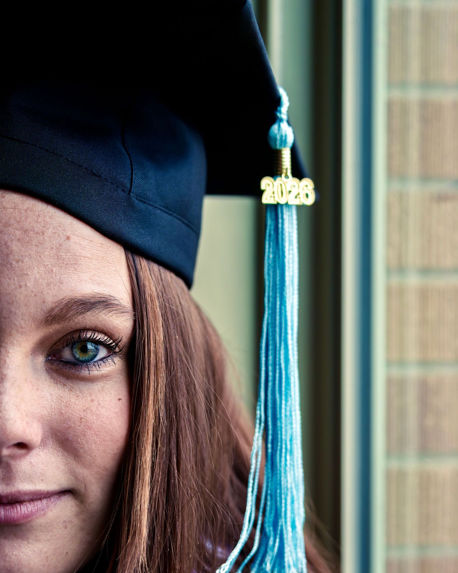 Close-up portrait of a young woman wearing a 2026 graduation cap with teal tassel.