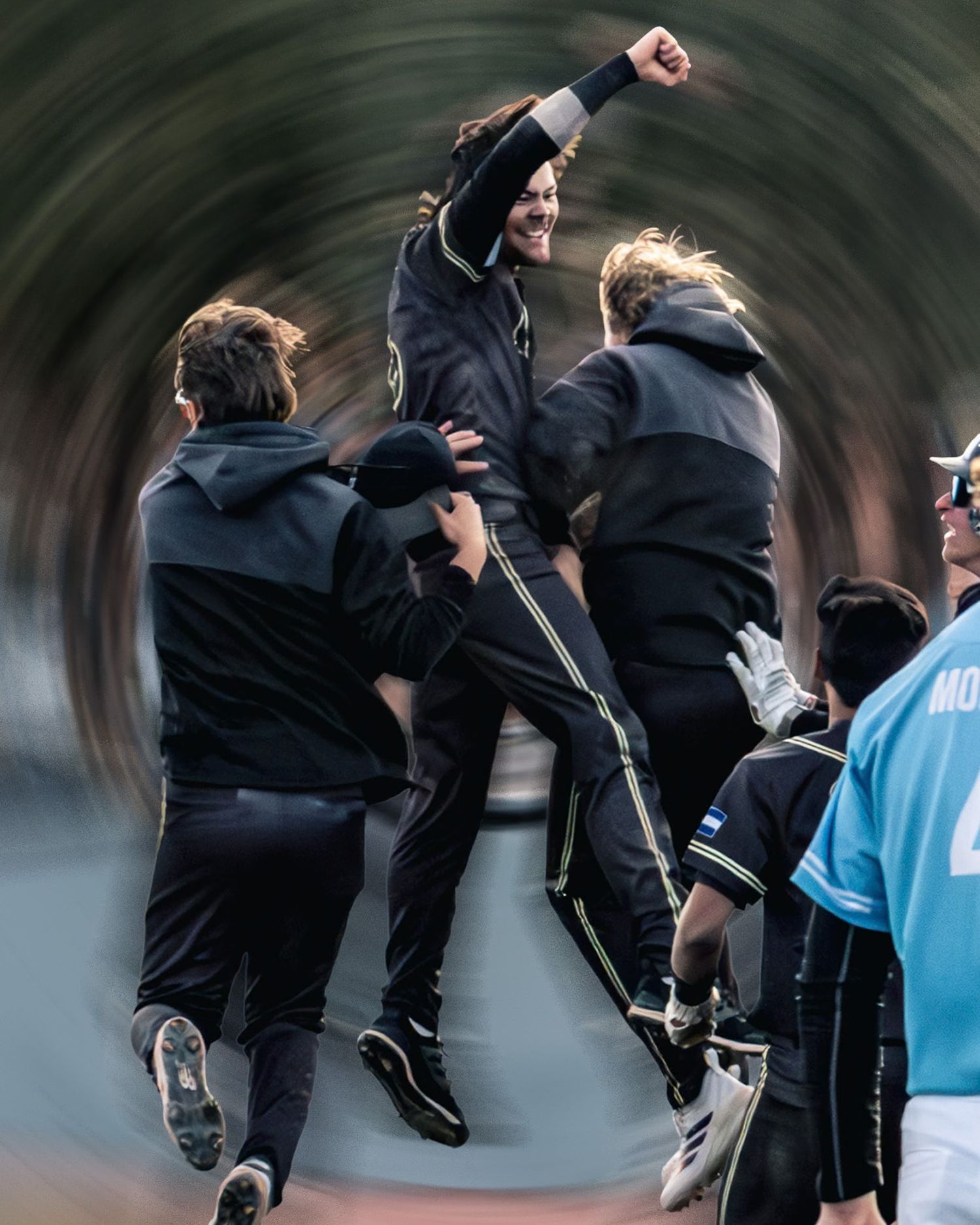 Athletes in black celebrate a victory, one player lifted with fist raised in triumph during an outdoor sports event.