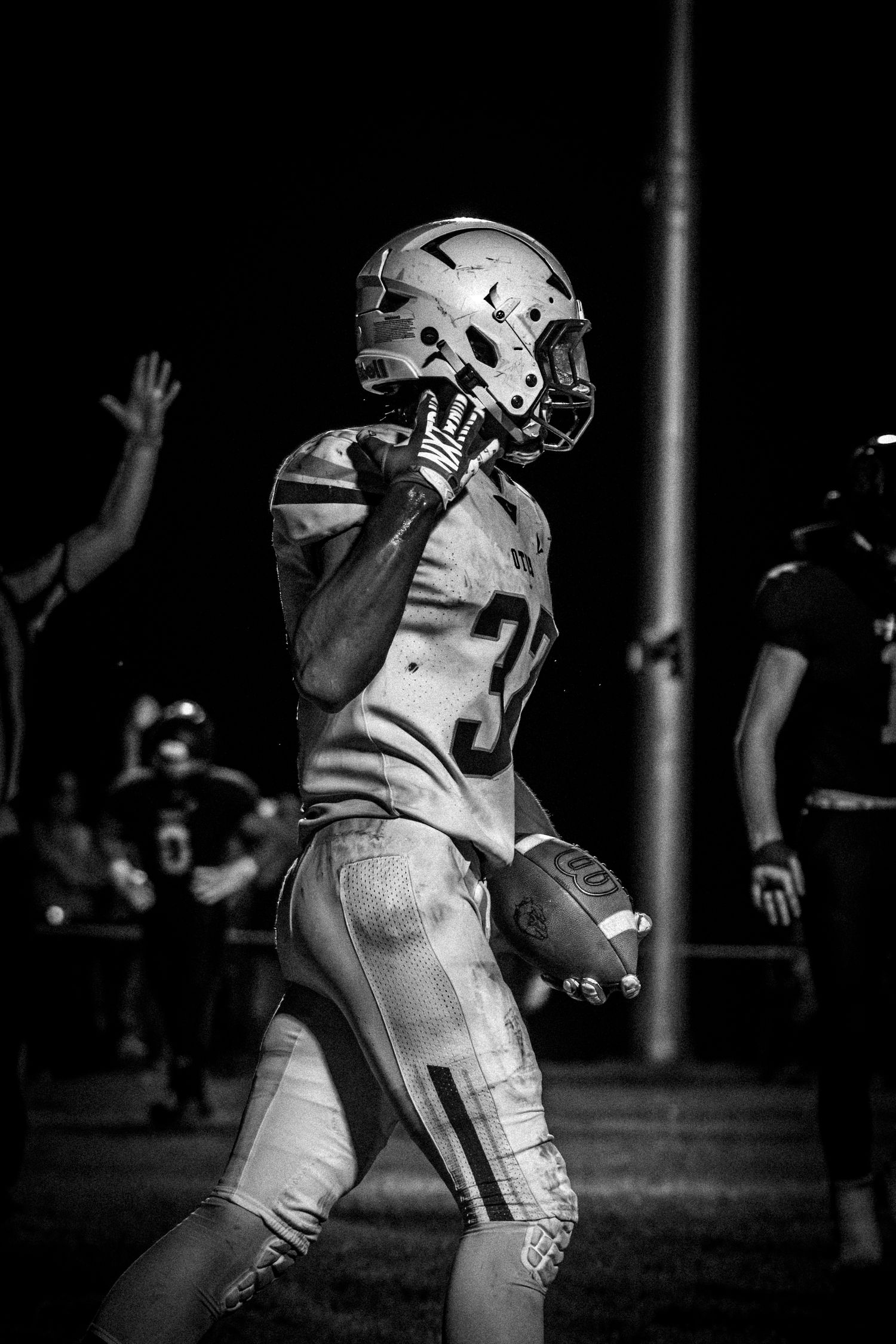 Black and white photo of football player number 32 carrying the ball during a night game.